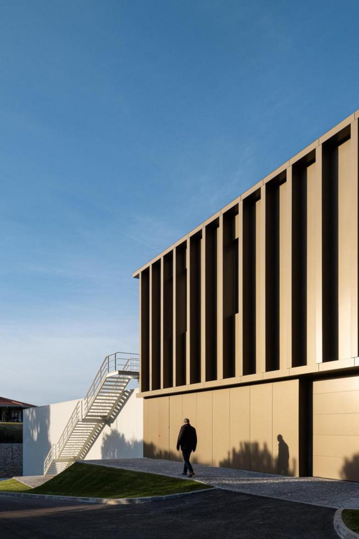 Vista do pavimento exterior em betão, que se estende desde a entrada, reforçando a integração do edifício no terreno. — EDIFÍCIO-SEDE PRF arquitectura Impare Arquitectura fotografia Ivo Tavares