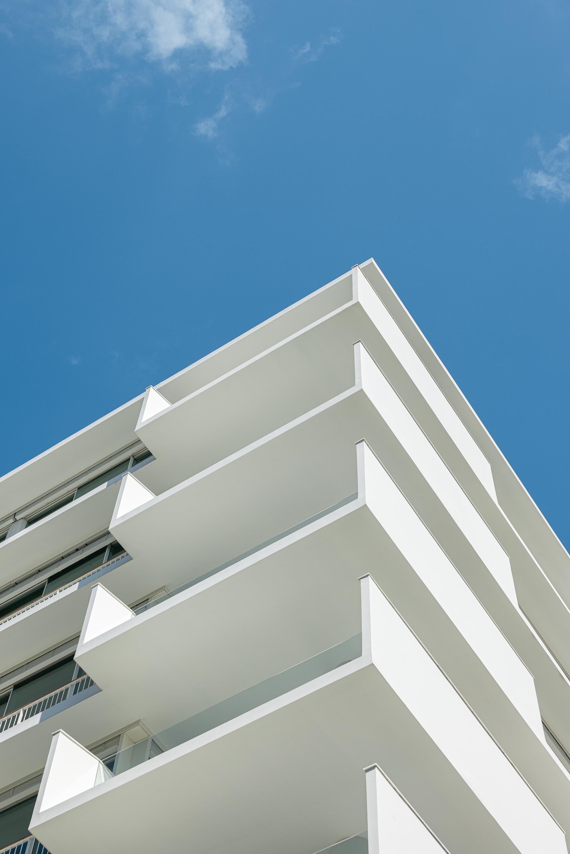 Canto da fachada com varandas em consola de reboco branco e guardas de vidro, criando um ritmo horizontal — Edifício Natura arquitectura Visioarq Arquitectos fotografia Ivo Tavares