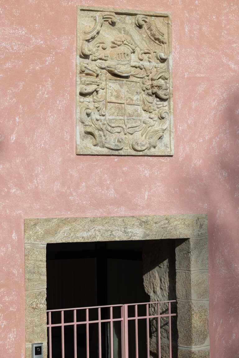 Detalhe da fachada rosa com brasão em pedra granítica e vão de entrada emoldurado — Boutique Apartments arquitectura HPA fotografia Ivo Tavares