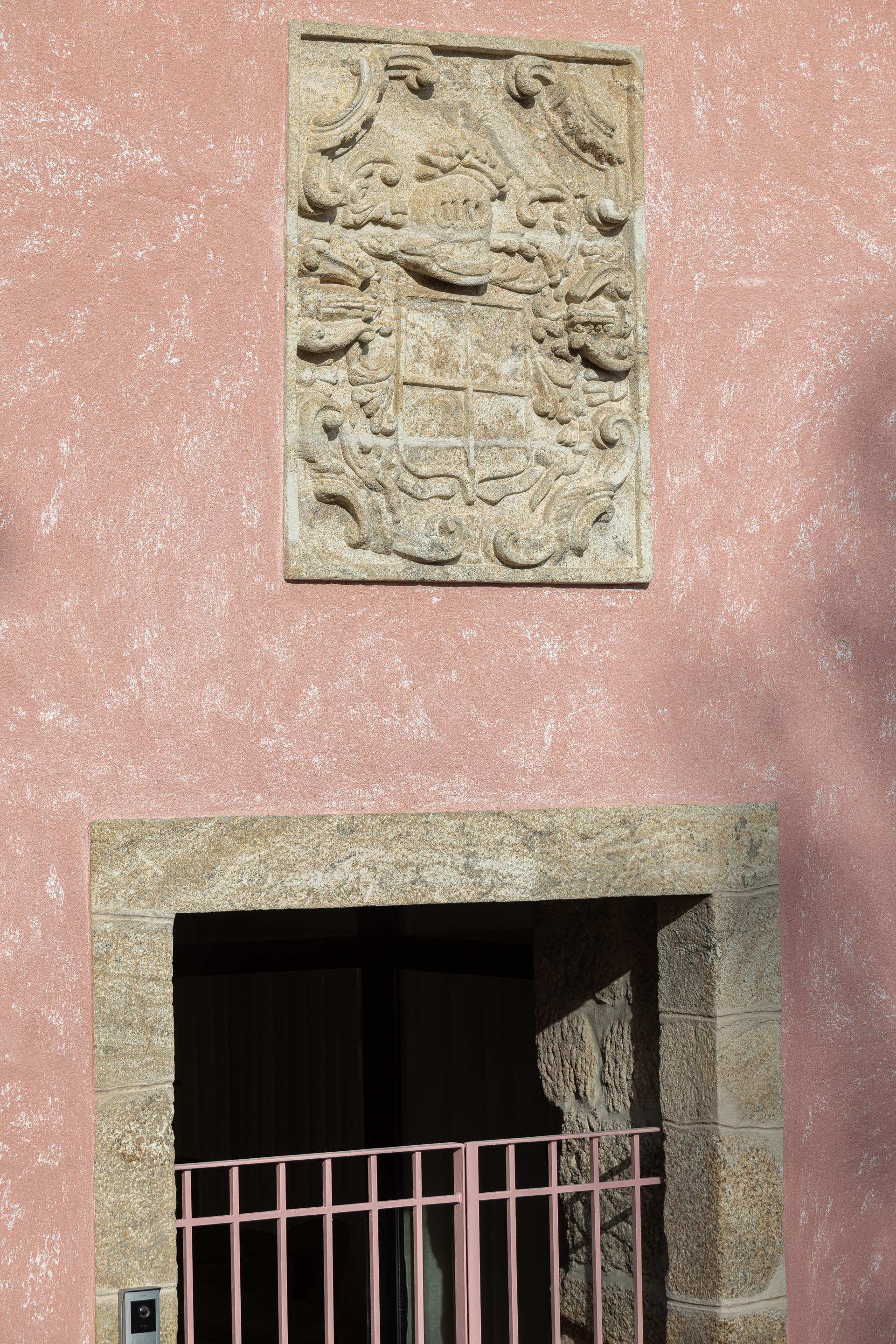 Detalhe da fachada rosa com brasão em pedra granítica e vão de entrada emoldurado — Boutique Apartments arquitectura HPA fotografia Ivo Tavares