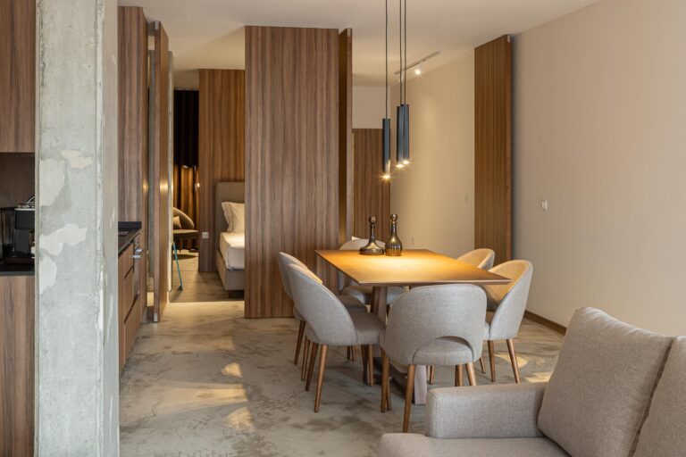 Interior de sala e cozinha em plano aberto, com pavimento em betão e painéis de madeira — Boutique Apartments arquitectura HPA fotografia Ivo Tavares