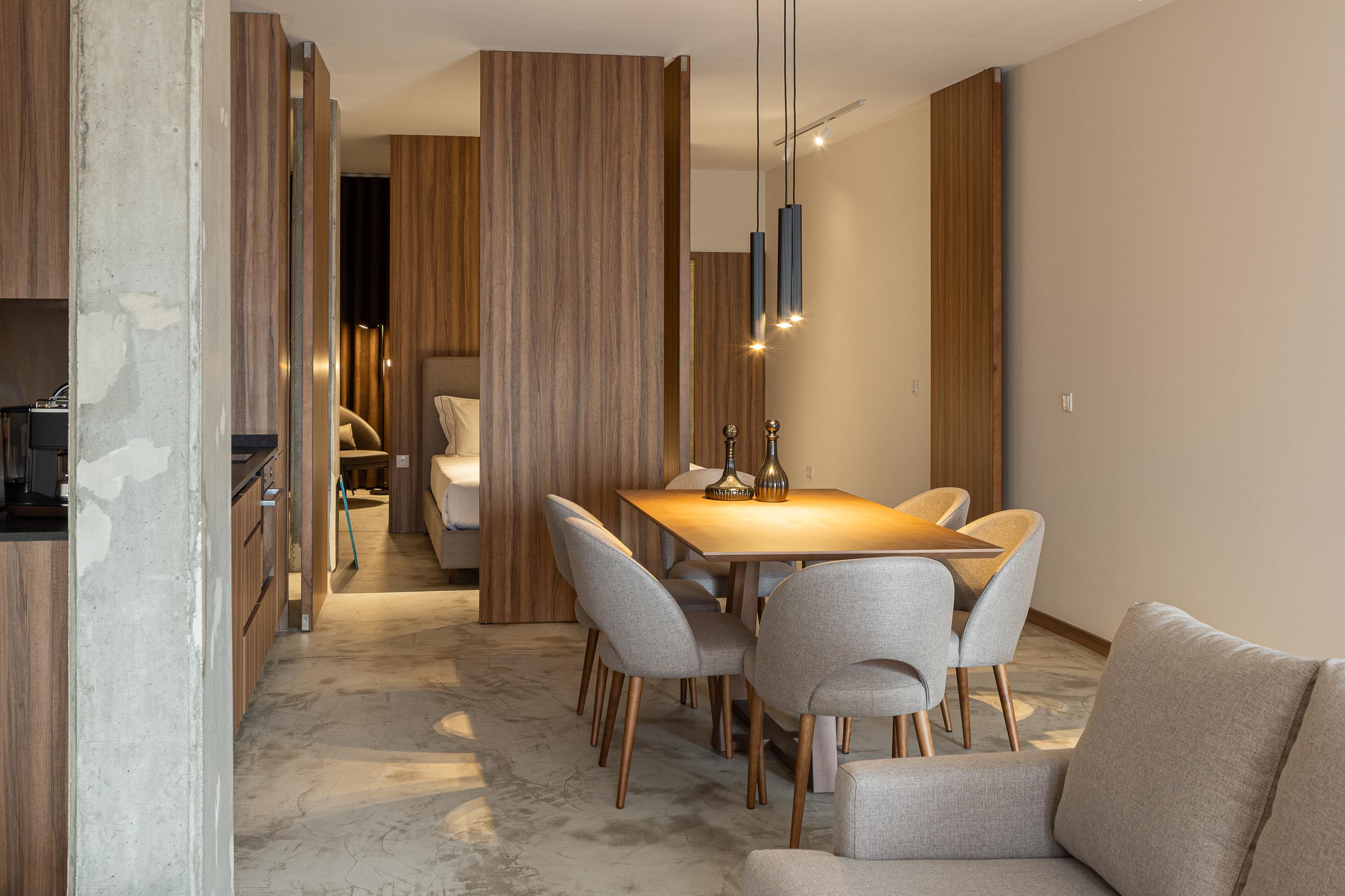 Interior de sala e cozinha em plano aberto, com pavimento em betão e painéis de madeira — Boutique Apartments arquitectura HPA fotografia Ivo Tavares