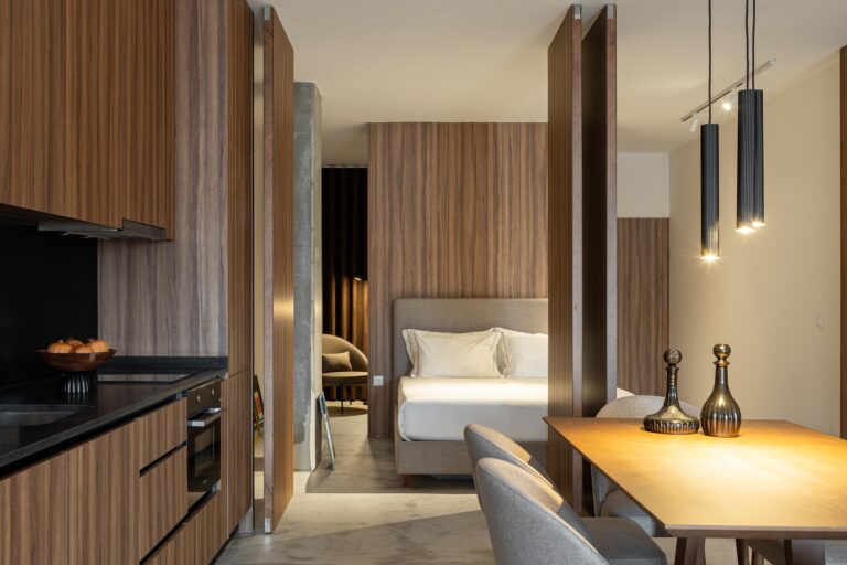 Cozinha e quarto integrados, com mobiliário em madeira e pavimento em betão cinzento — Boutique Apartments arquitectura HPA fotografia Ivo Tavares