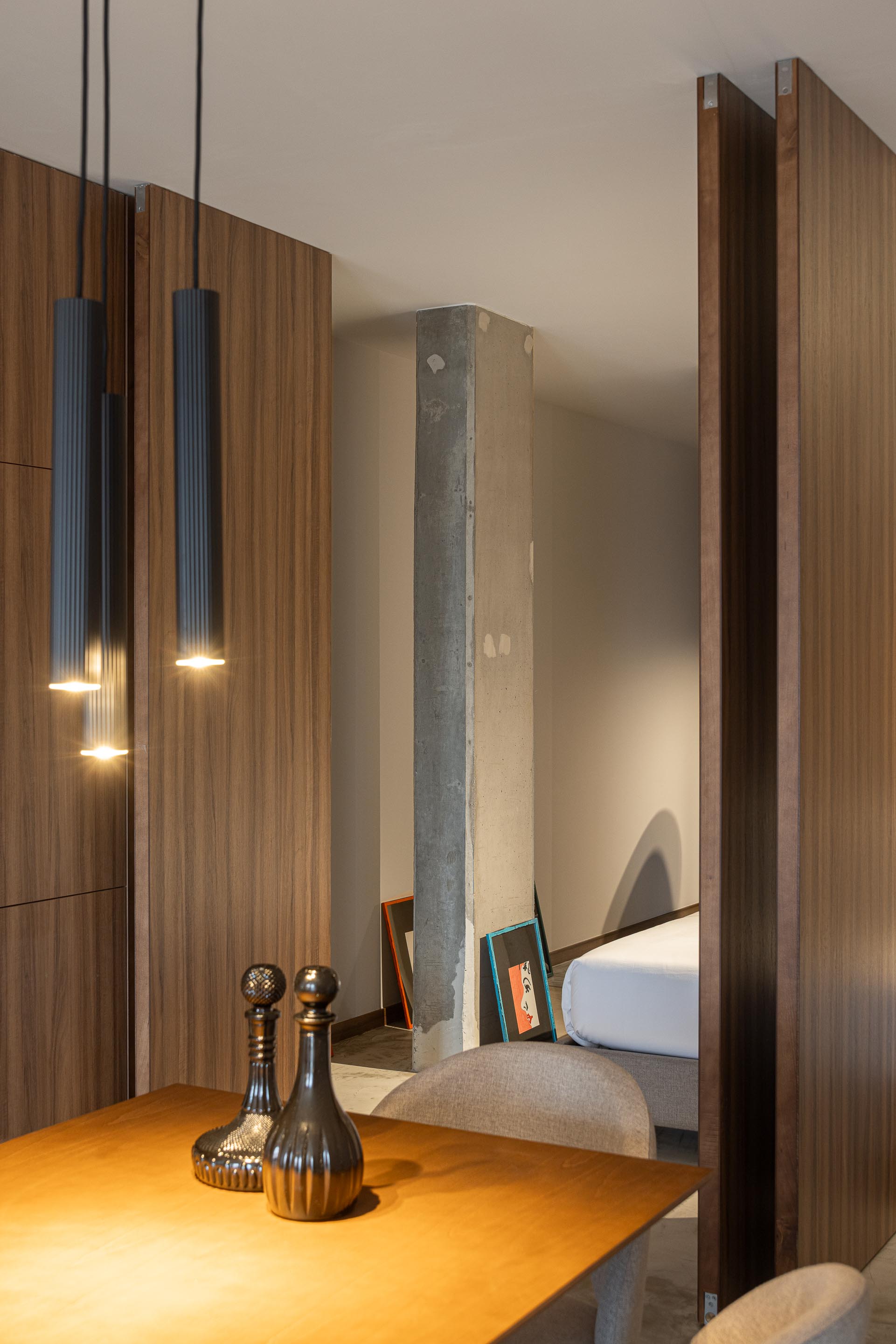 Sala de estar com pilar em betão aparente e painéis de madeira que separam o quarto — Boutique Apartments arquitectura HPA fotografia Ivo Tavares
