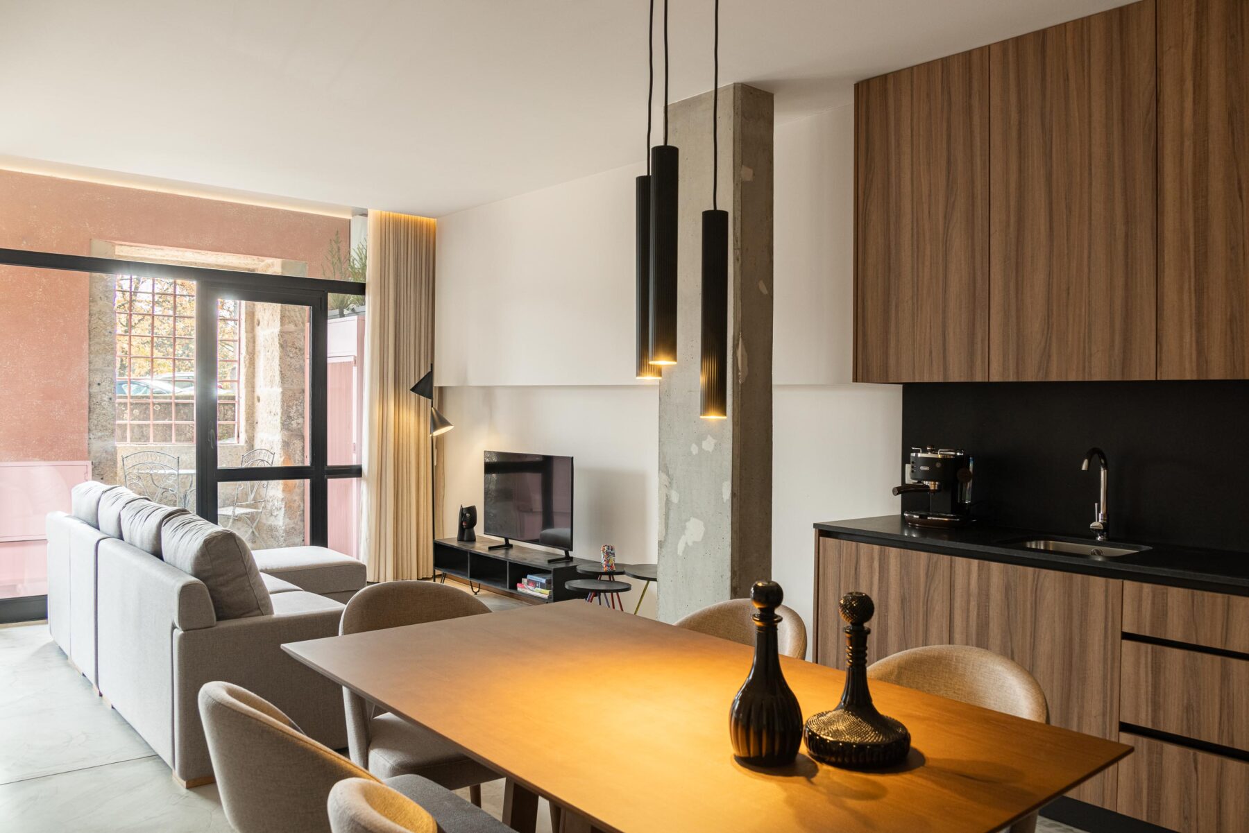 Sala de estar e jantar com pavimento em betão, candeeiros suspensos e vão envidraçado — Boutique Apartments arquitectura HPA fotografia Ivo Tavares