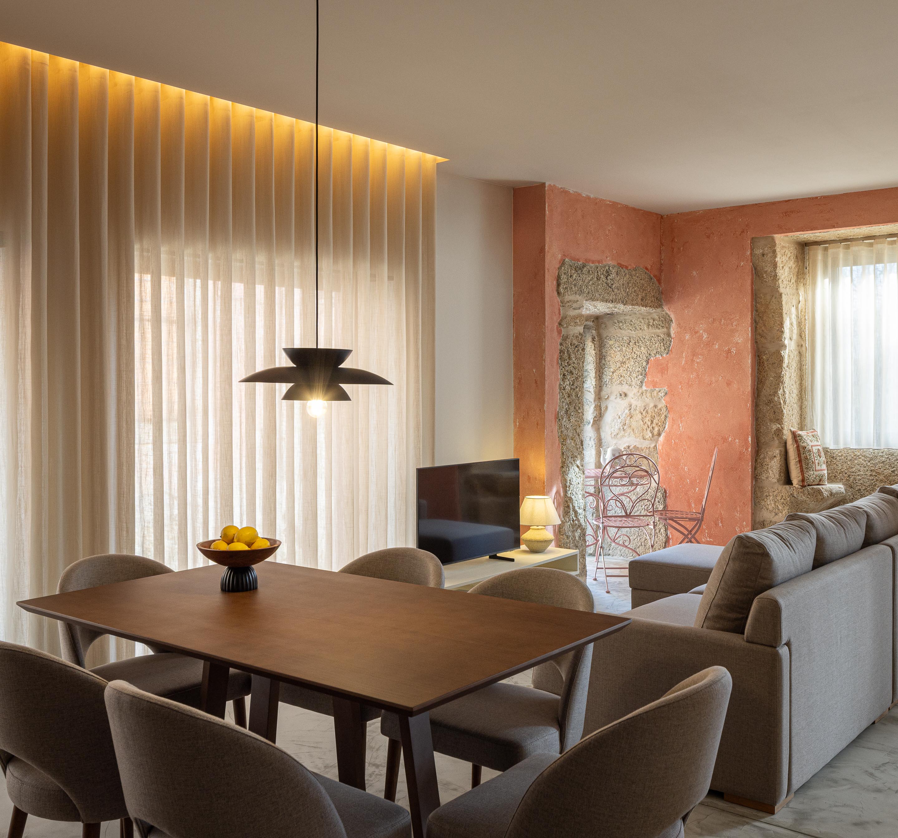Sala de jantar e estar com cortinas claras, candeeiro de design e namoradeira de pedra — Boutique Apartments arquitectura HPA fotografia Ivo Tavares