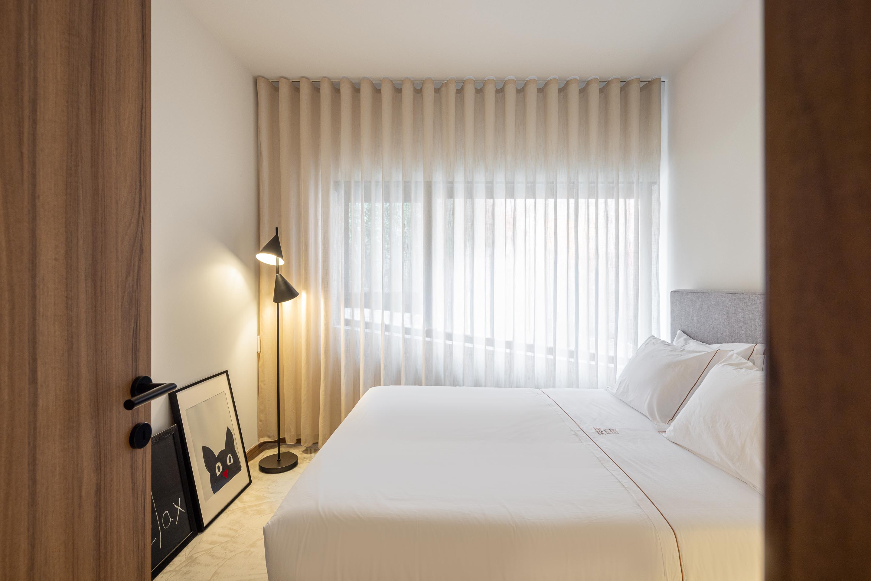 Quarto com pavimento em betão, cortinas claras e candeeiro de pé preto — Boutique Apartments arquitectura HPA fotografia Ivo Tavares