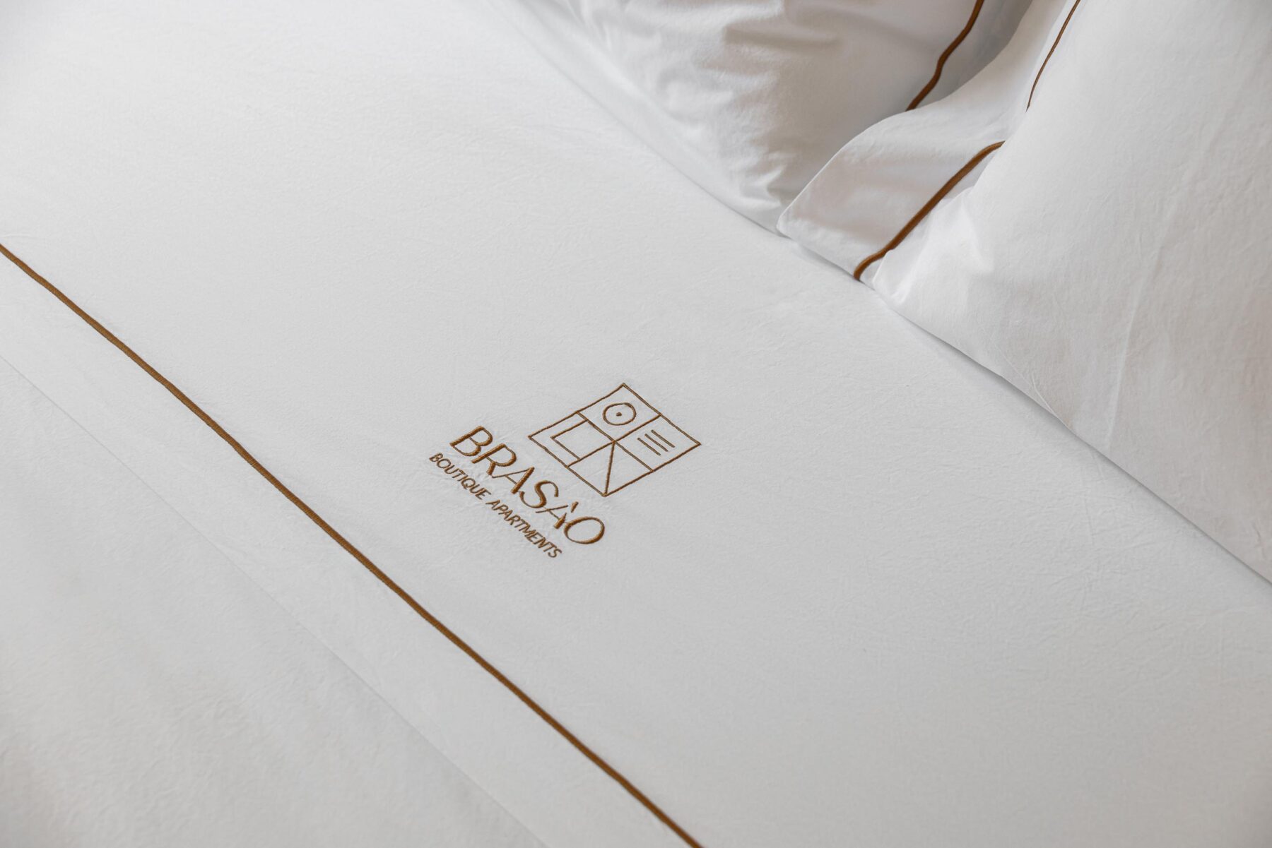 Detalhe da cama no quarto com roupa branca e bordado discreto — Boutique Apartments arquitectura HPA fotografia Ivo Tavares