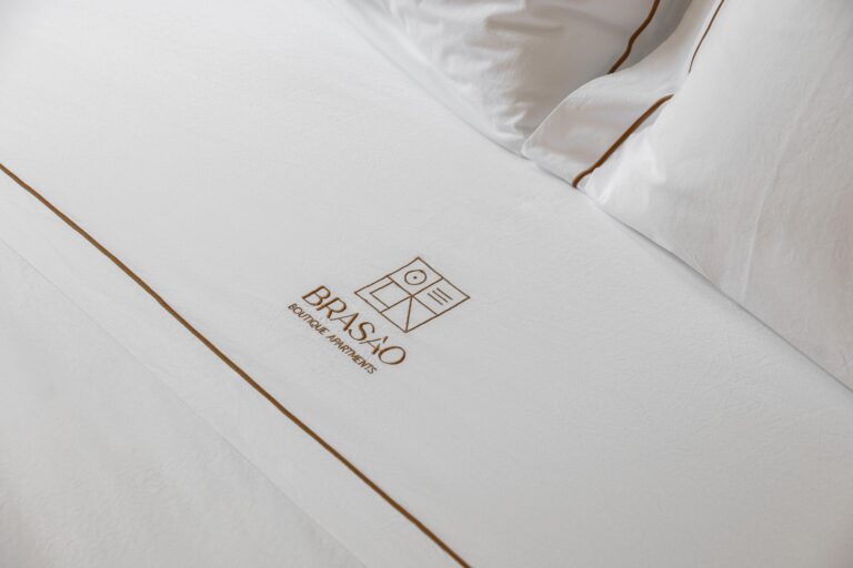 Detalhe da cama no quarto com roupa branca e bordado discreto — Boutique Apartments arquitectura HPA fotografia Ivo Tavares