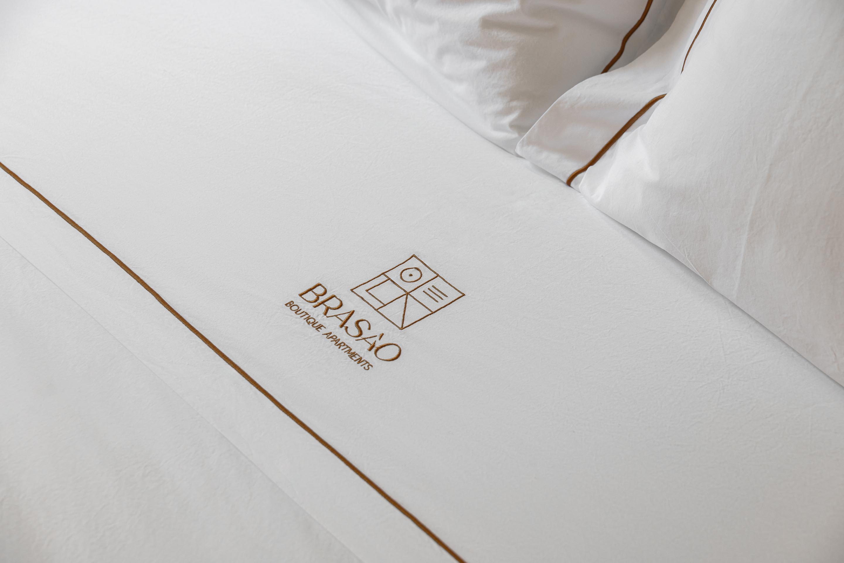 Detalhe da cama no quarto com roupa branca e bordado discreto — Boutique Apartments arquitectura HPA fotografia Ivo Tavares