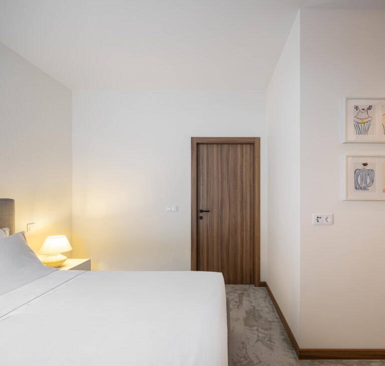 Quarto com pavimento em betão, paredes brancas e porta de madeira — Boutique Apartments arquitectura HPA fotografia Ivo Tavares