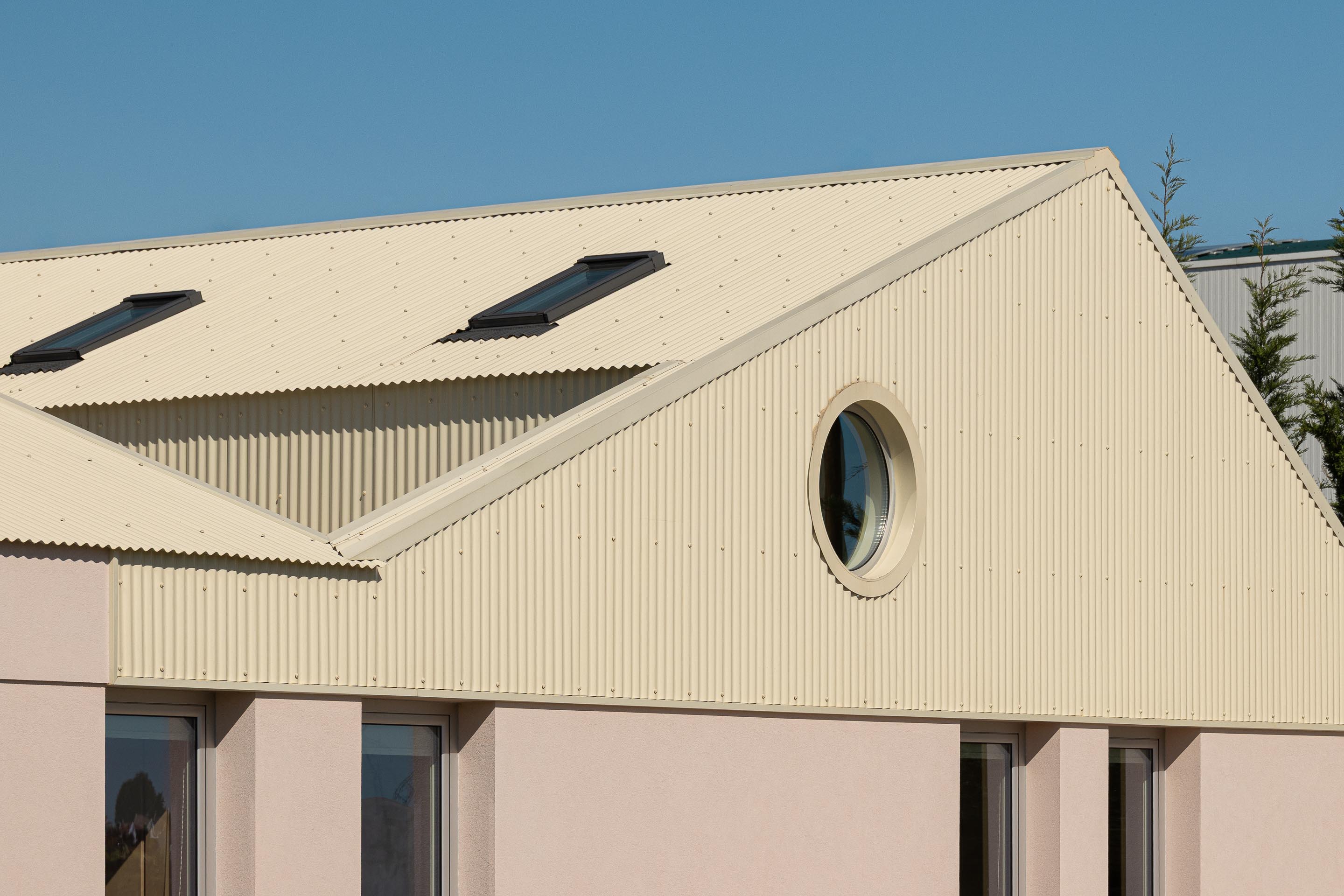 Detalhe da cobertura inclinada em chapa metálica bege, com claraboias e empena revestida a chapa ondulada — Casa do Alpendre arquitectura Vasco Burnay Arquitectura fotografia Ivo Tavares