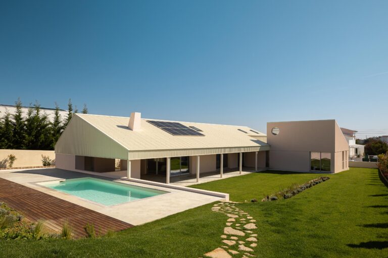Vista aérea da moradia em L, com cobertura inclinada, piscina e extenso relvado sob céu azul — Casa do Alpendre arquitectura Vasco Burnay Arquitectura fotografia Ivo Tavares
