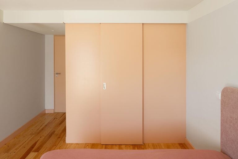 Interior de quarto com pavimento em madeira e armários embutidos de cor pêssego, com portas de correr — Casa do Alpendre arquitectura Vasco Burnay Arquitectura fotografia Ivo Tavares
