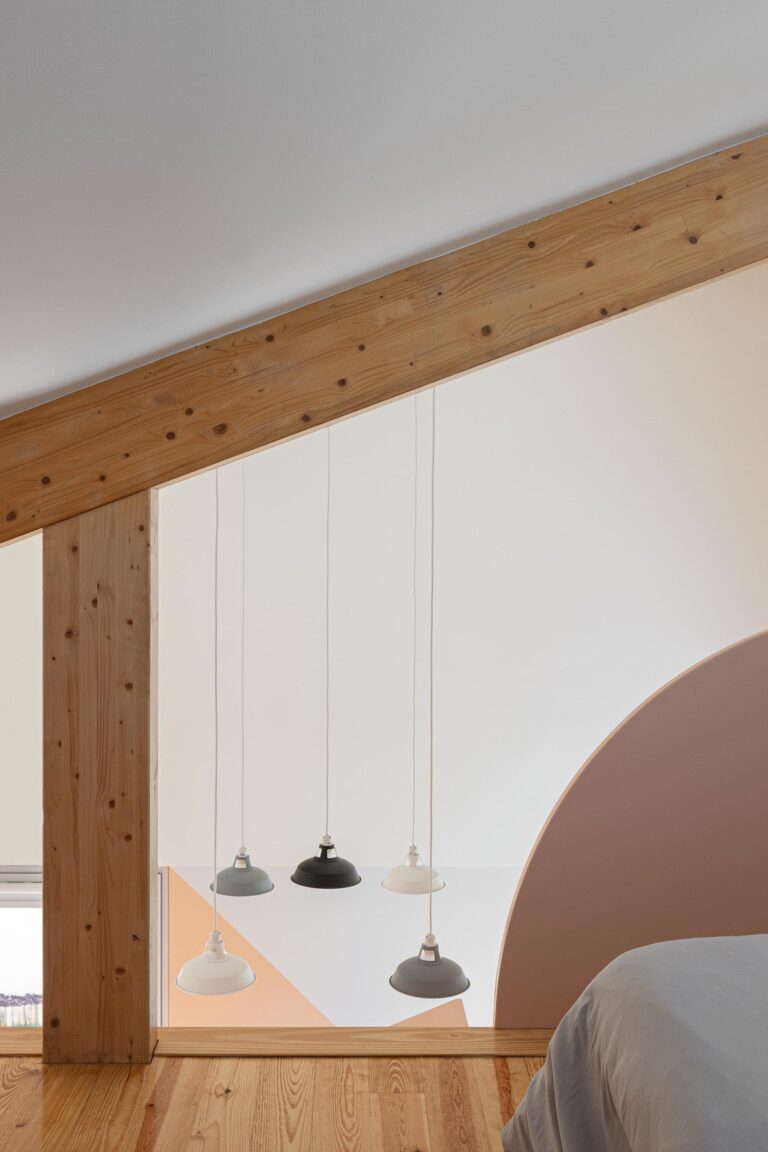 Detalhe do sótão com estrutura de madeira exposta e candeeiros suspensos, visto do quarto — Casa do Alpendre arquitectura Vasco Burnay Arquitectura fotografia Ivo Tavares