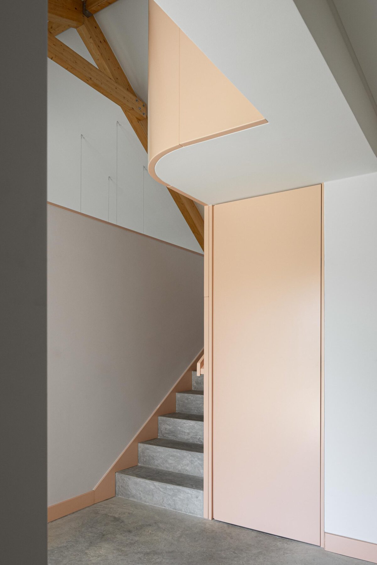 Escada interior com degraus em pedra cinzenta e painel lateral pêssego, sob estrutura de madeira — Casa do Alpendre arquitectura Vasco Burnay Arquitectura fotografia Ivo Tavares