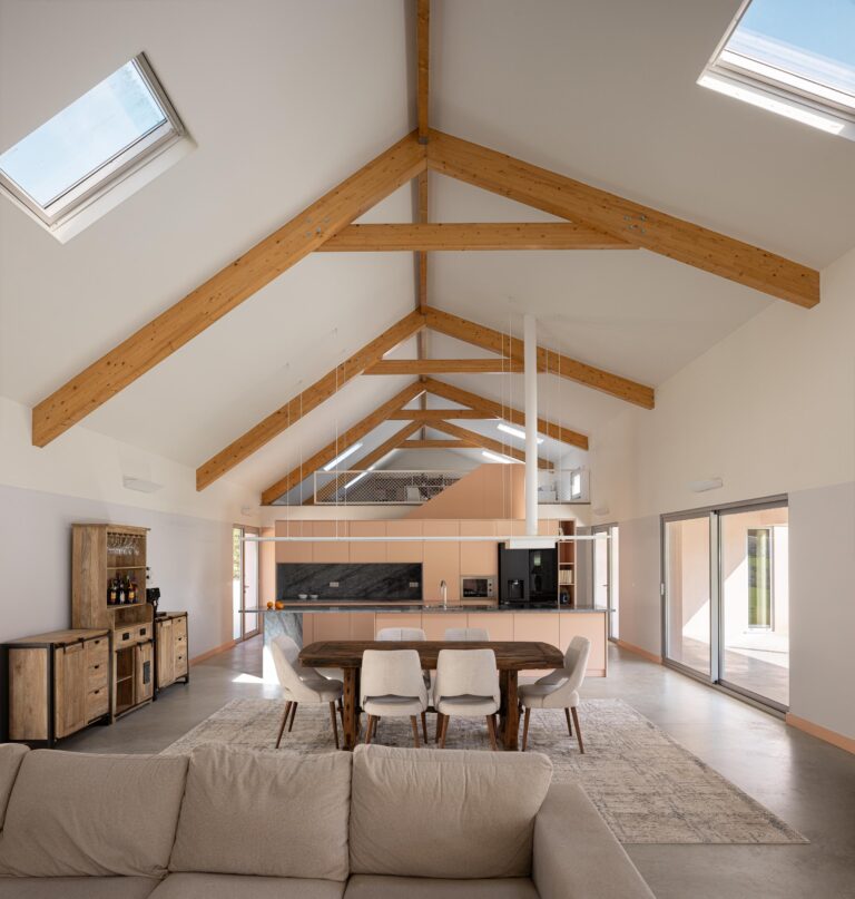 Sala e cozinha com pé-direito duplo, estrutura de madeira exposta e iluminação zenital por claraboias — Casa do Alpendre arquitectura Vasco Burnay Arquitectura fotografia Ivo Tavares