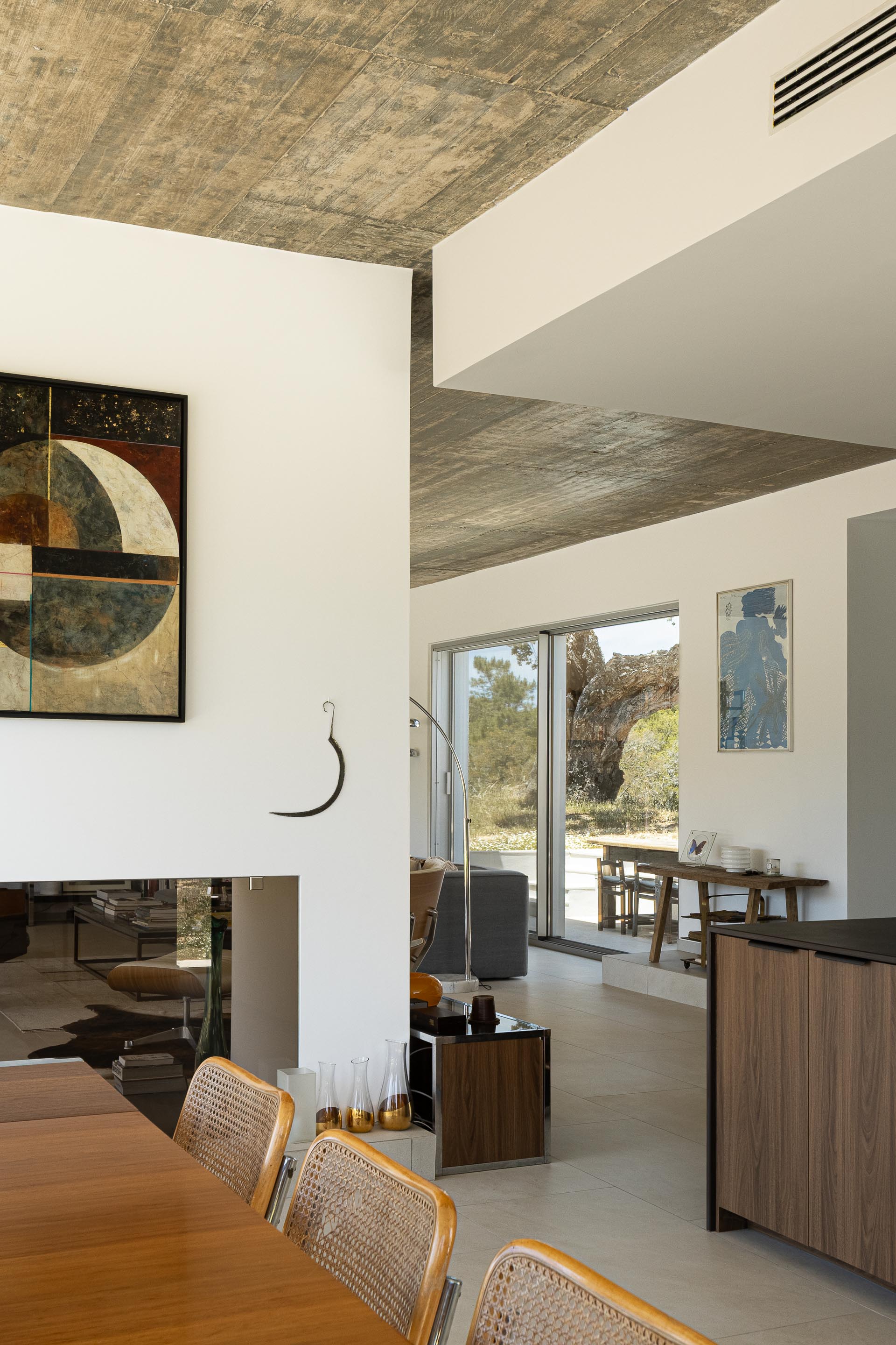 Sala com pavimento em cerâmica clara e cobertura em betão aparente, com lareira e vista para a paisagem exterior — Casa M Ariane fotografia Ivo Tavares