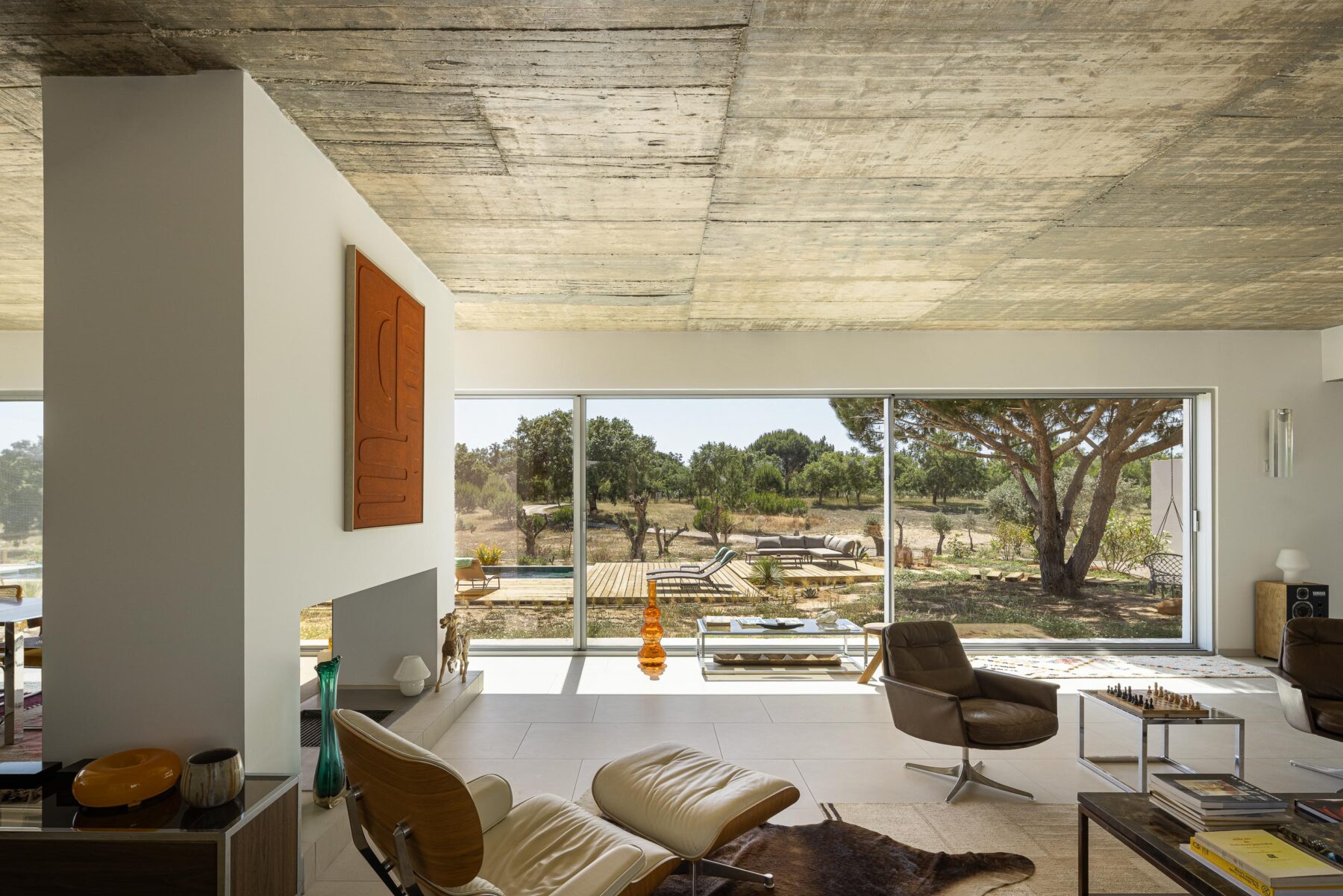 Sala de estar com pavimento em cerâmica clara, cobertura em betão aparente e grandes vãos com vista para a piscina — Casa M Ariane fotografia Ivo Tavares