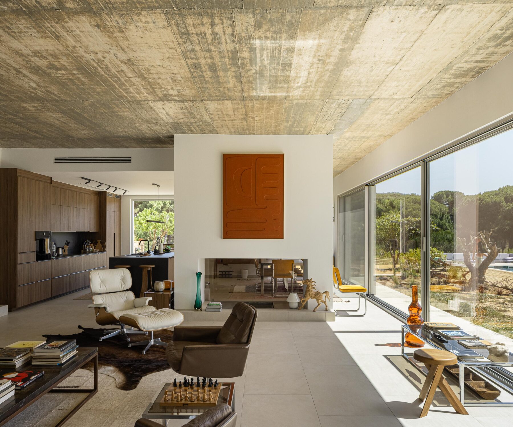 Sala de estar e cozinha em planta aberta com pavimento claro, cobertura em betão aparente e grandes vãos envidraçados — Casa M Ariane fotografia Ivo Tavares