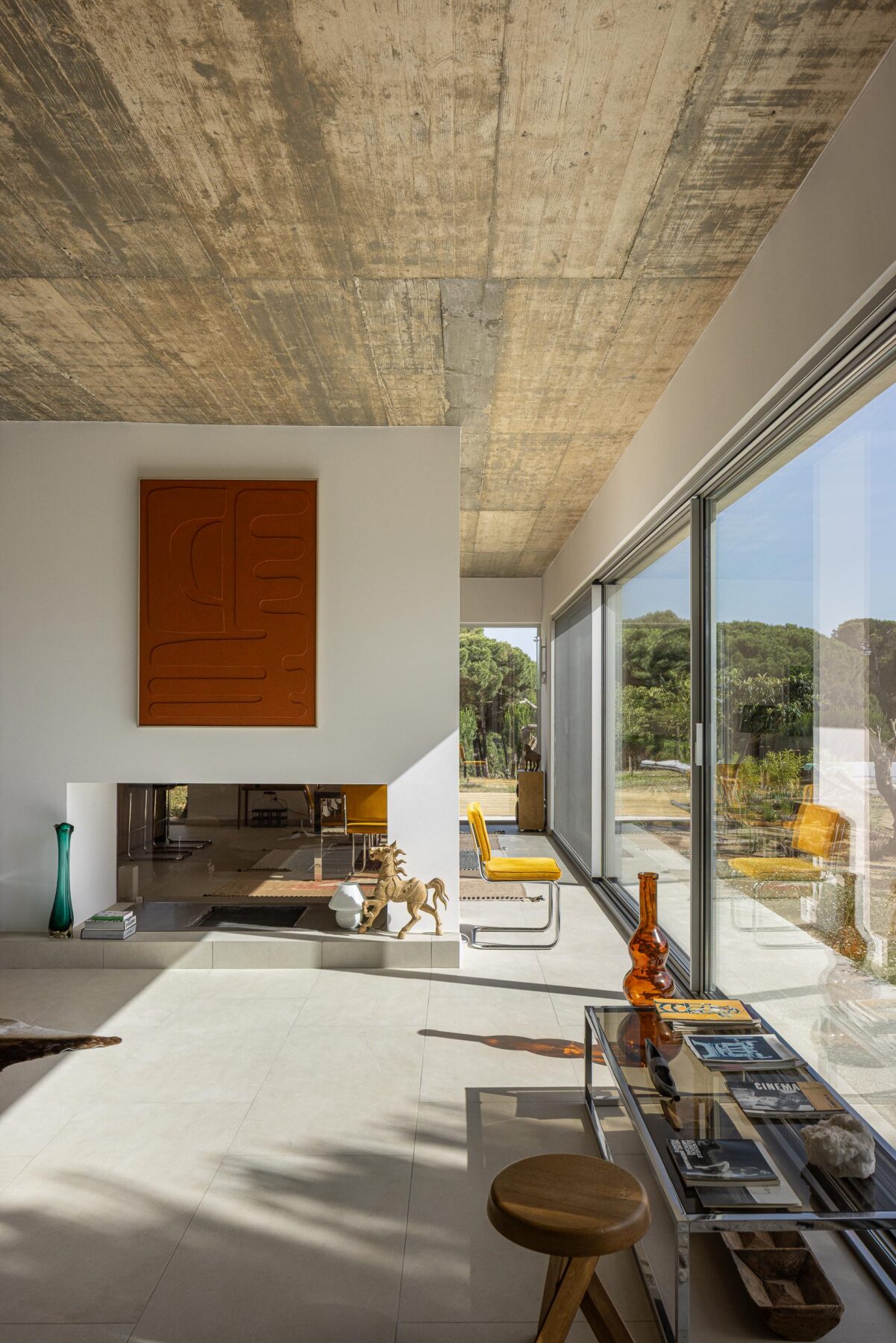 Sala de estar com pavimento claro, cobertura em betão aparente e grandes vãos com vista para a piscina e paisagem — Casa M Ariane fotografia Ivo Tavares