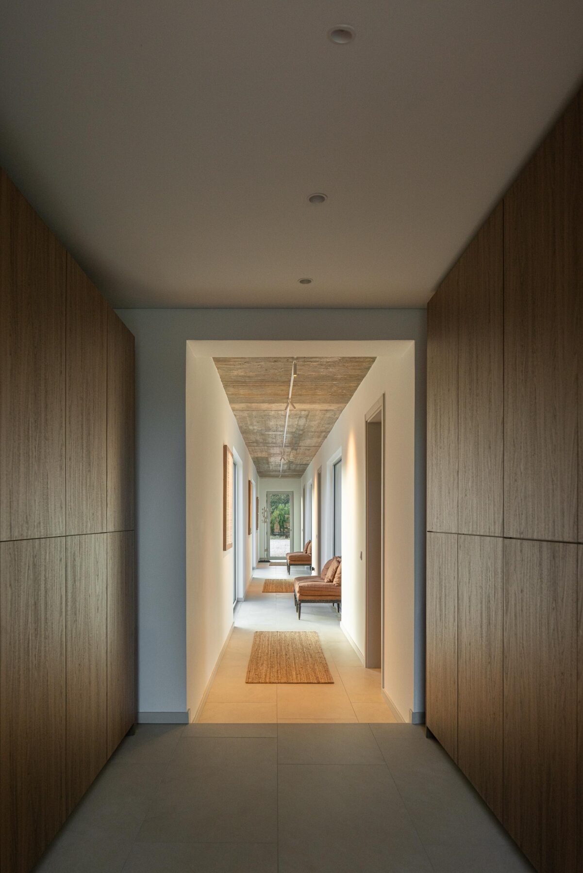 Corredor com pavimento em cerâmica clara, cobertura em betão aparente e armários em madeira natural embutidos — Casa M Ariane fotografia Ivo Tavares