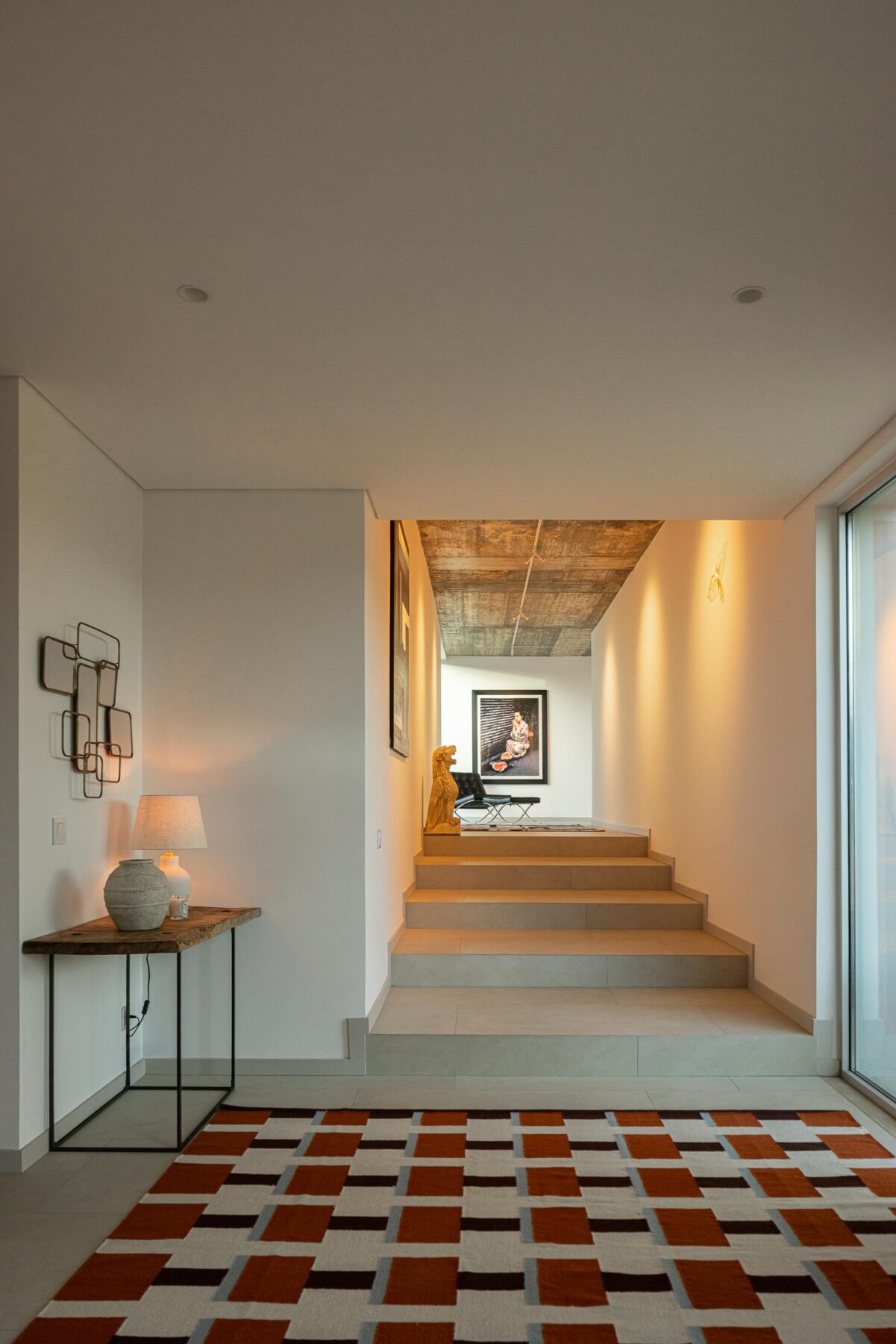 Hall de entrada com pavimento em cerâmica clara, escada e cobertura em betão aparente, com luz natural — Casa M Ariane fotografia Ivo Tavares