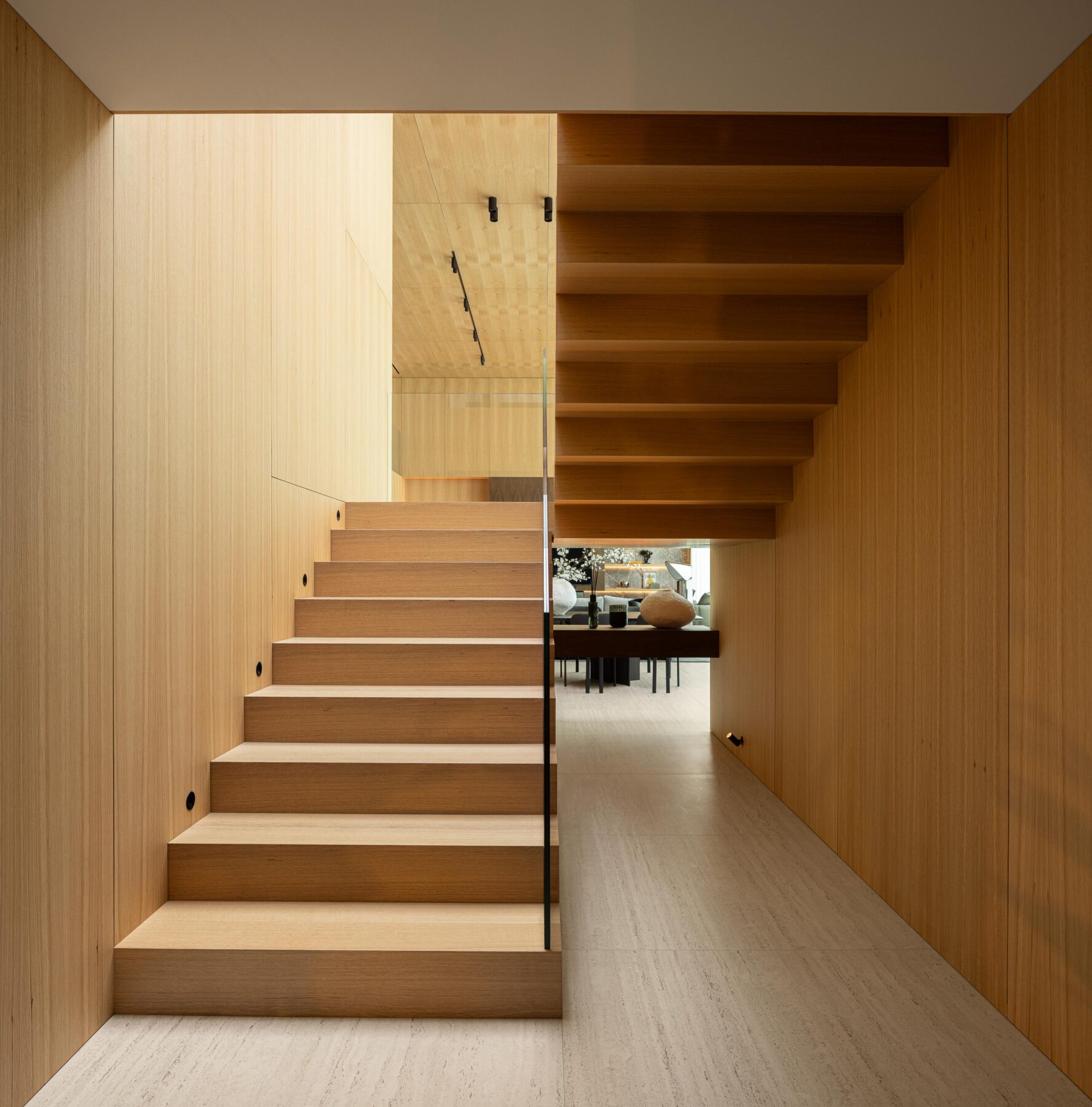 Escadaria com degraus e paredes em madeira mel, guarda-corpos em vidro estrutural e pavimento em pedra clara — Casa FJ arquitectura MIL870 + GRAUON fotografia Ivo Tavares