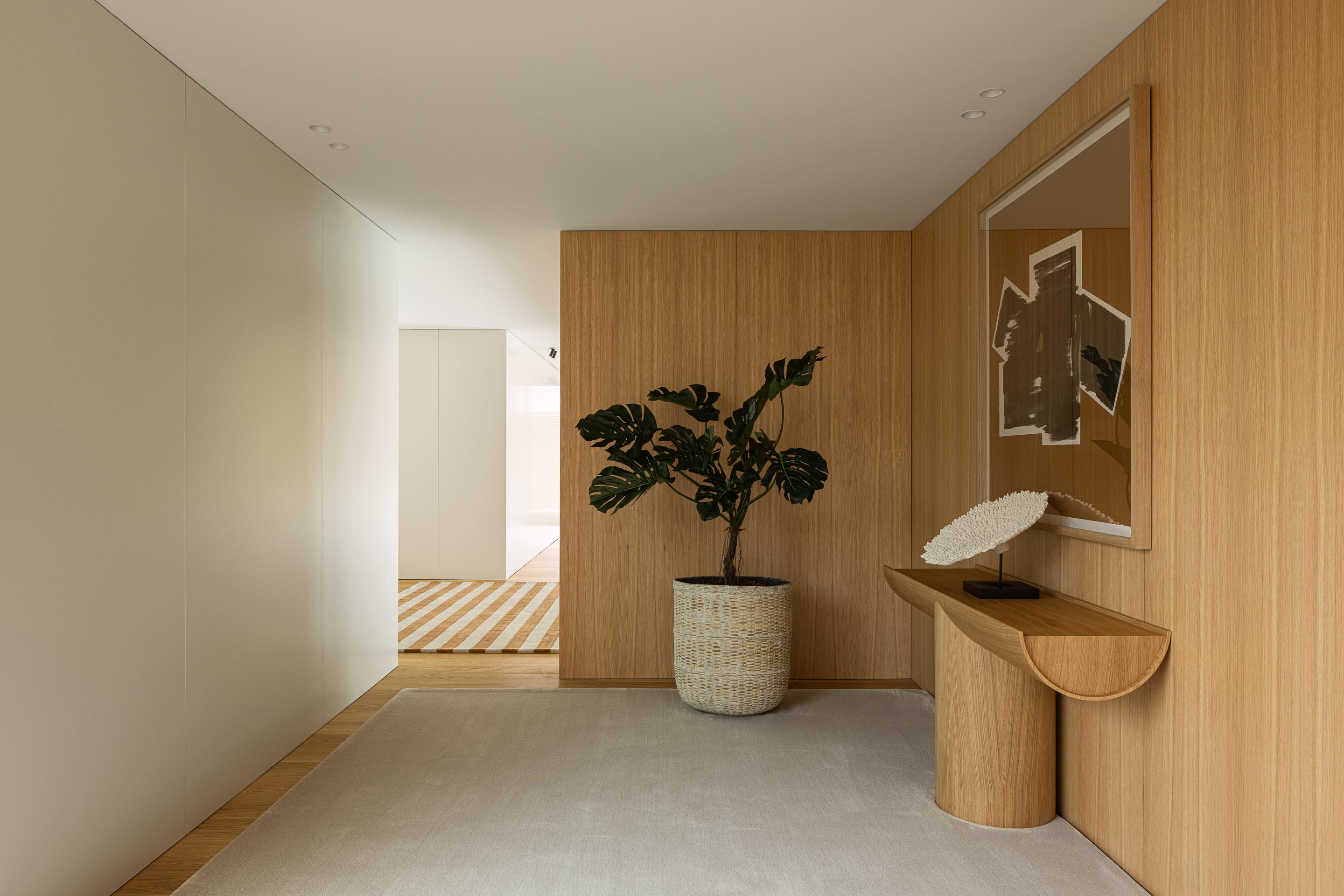 Corredor do pavimento superior com paredes brancas, revestimento em madeira mel e pavimento em madeira clara — Casa FJ arquitectura MIL870 + GRAUON fotografia Ivo Tavares