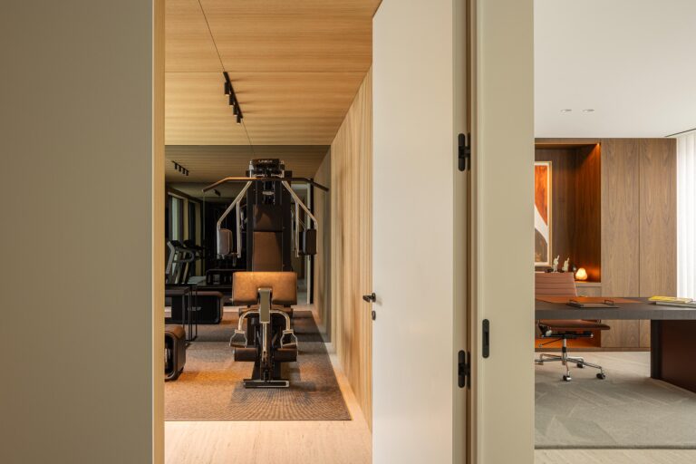 Ginásio com paredes e teto em madeira mel, pavimento em pedra clara e vista para escritório — Casa FJ arquitectura MIL870 + GRAUON fotografia Ivo Tavares