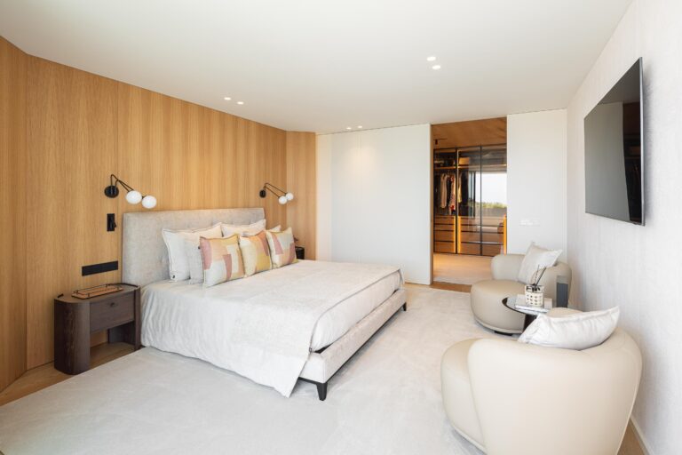 Quarto principal com parede em madeira mel, pavimento em alcatifa clara e acesso ao closet — Casa FJ arquitectura MIL870 + GRAUON fotografia Ivo Tavares
