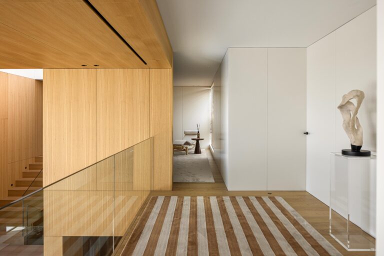 Hall do pavimento superior com pavimento em madeira clara, guarda-corpos em vidro e paredes em madeira mel — Casa FJ arquitectura MIL870 + GRAUON fotografia Ivo Tavares