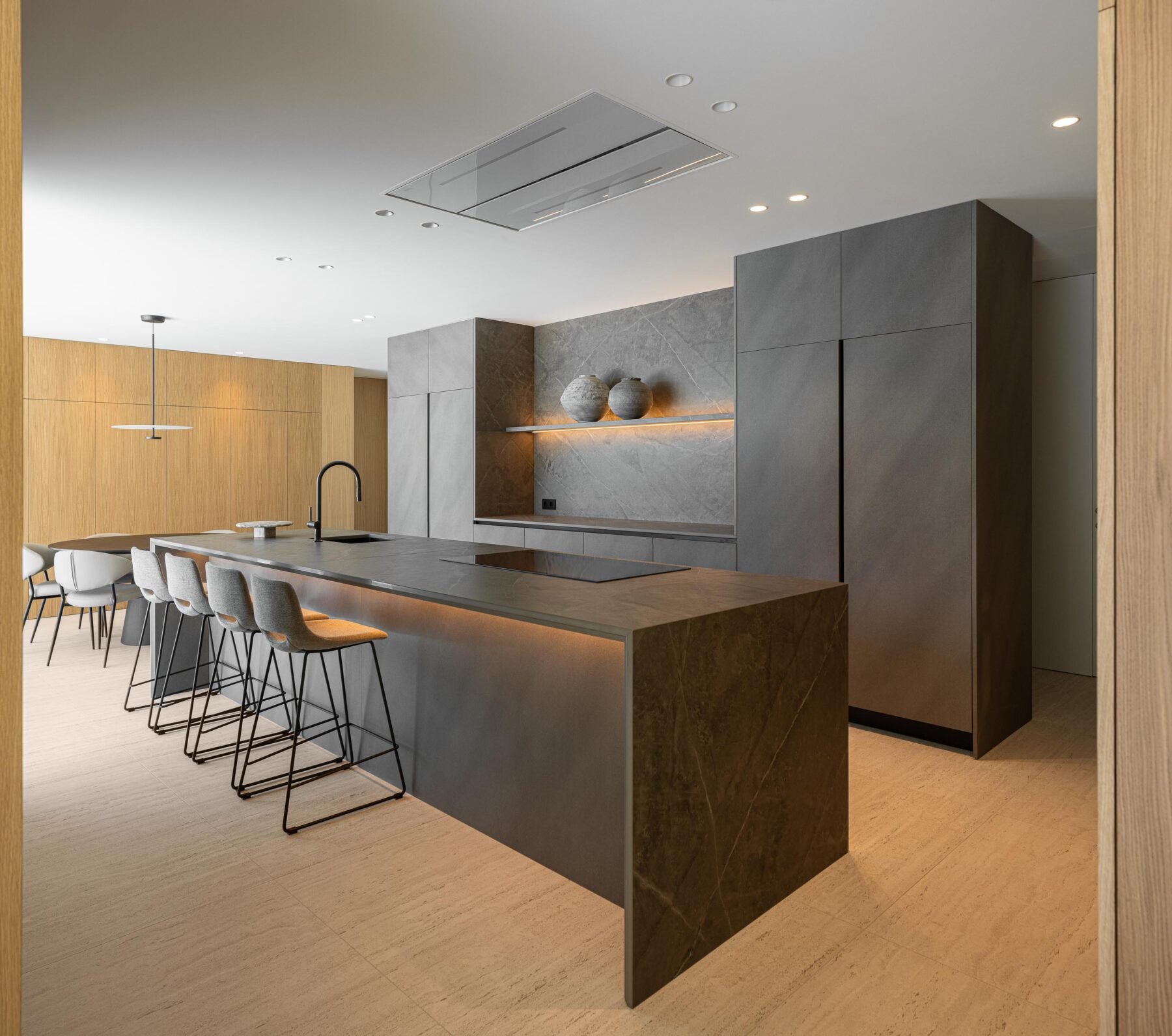 Cozinha com ilha e armários em pedra escura, pavimento em pedra clara e iluminação integrada — Casa FJ arquitectura MIL870 + GRAUON fotografia Ivo Tavares