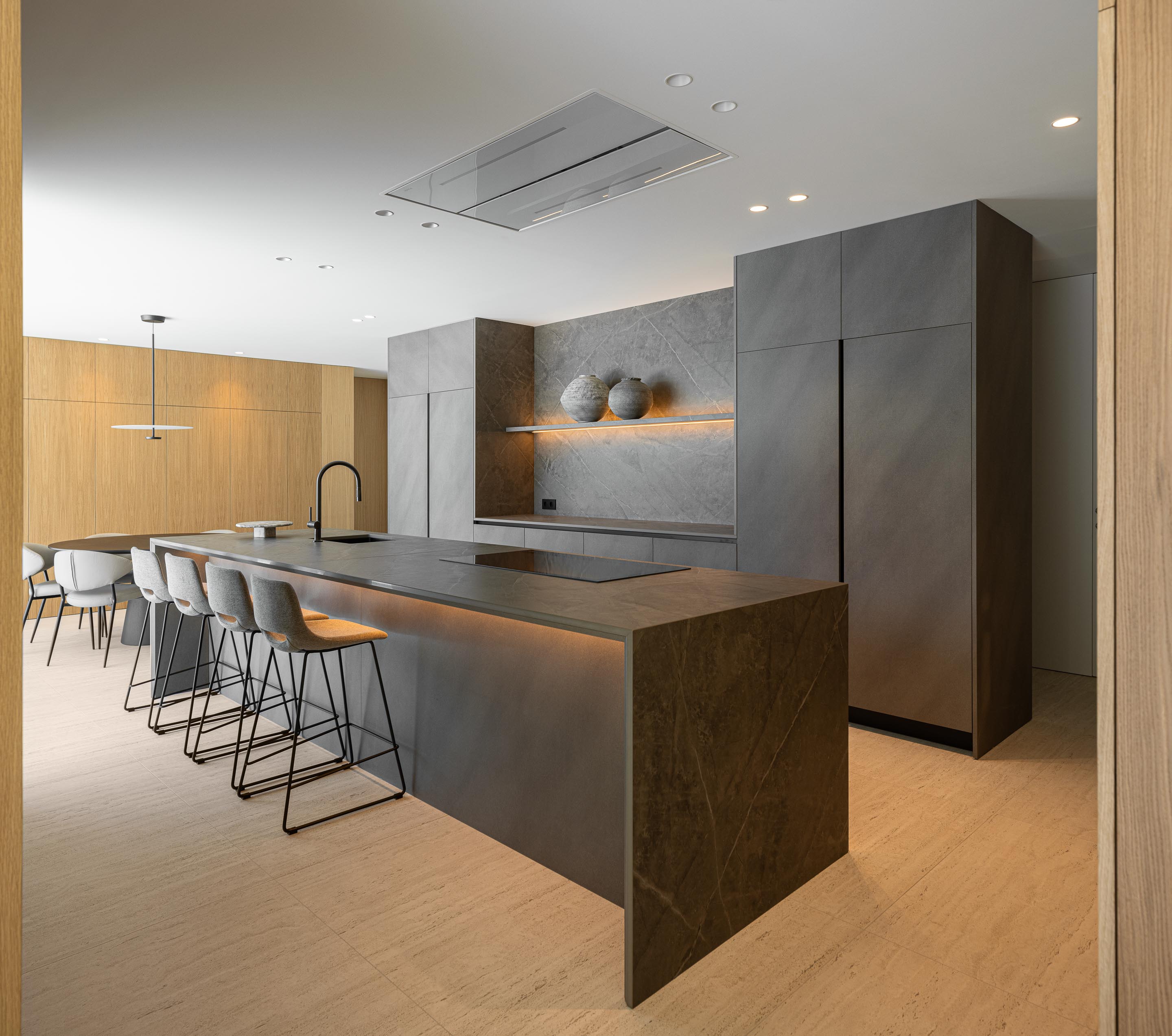 Cozinha com ilha e armários em pedra escura, pavimento em pedra clara e iluminação integrada — Casa FJ arquitectura MIL870 + GRAUON fotografia Ivo Tavares