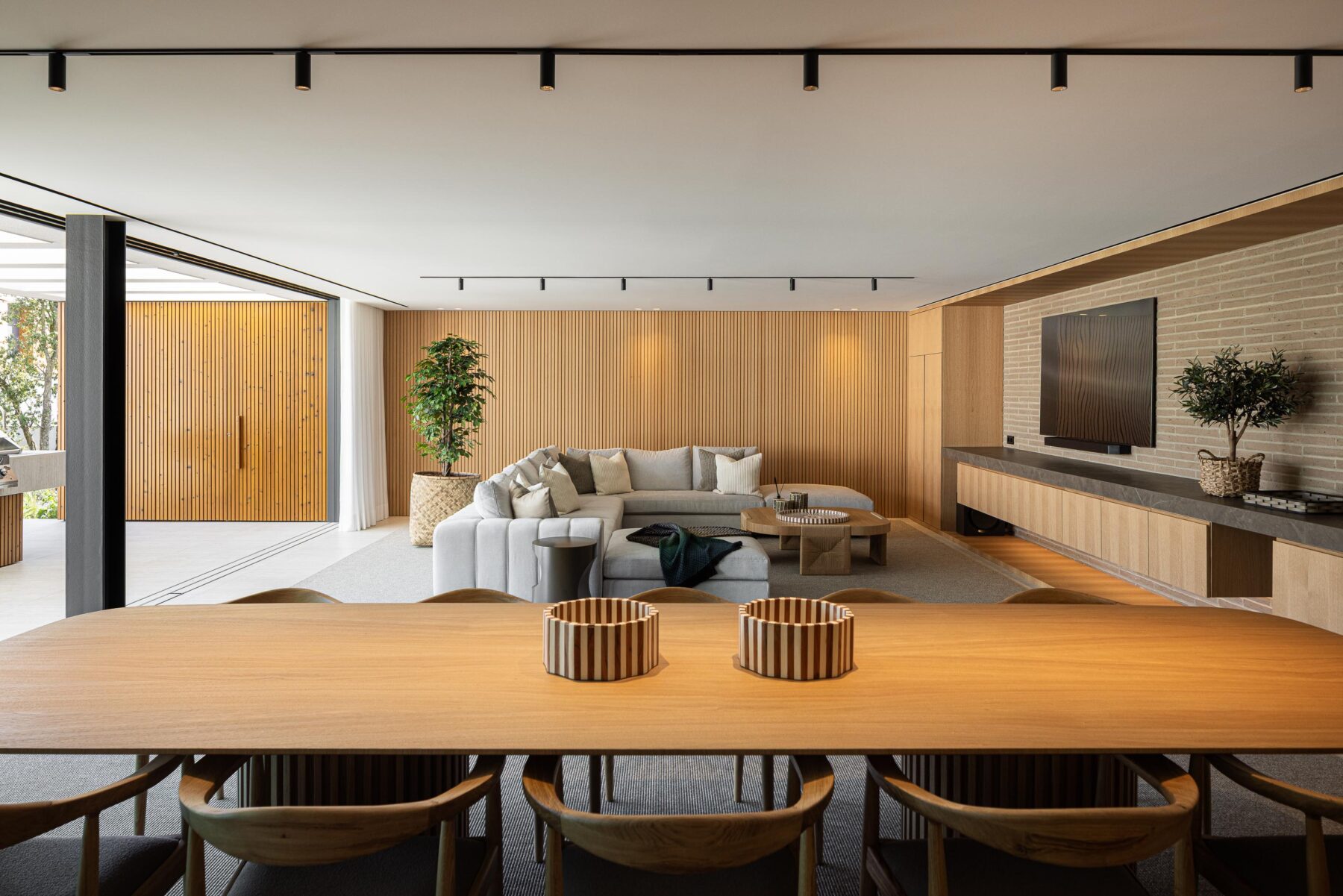 Sala de estar e jantar com pavimento em alcatifa, parede ripada em madeira mel e mesa de jantar — Casa FJ arquitectura MIL870 + GRAUON fotografia Ivo Tavares