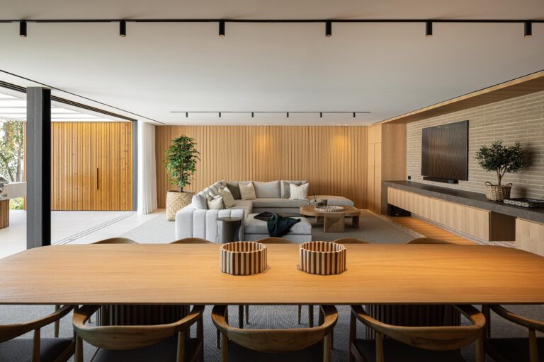 Sala de estar e jantar com pavimento em alcatifa, parede ripada em madeira mel e mesa de jantar — Casa FJ arquitectura MIL870 + GRAUON fotografia Ivo Tavares
