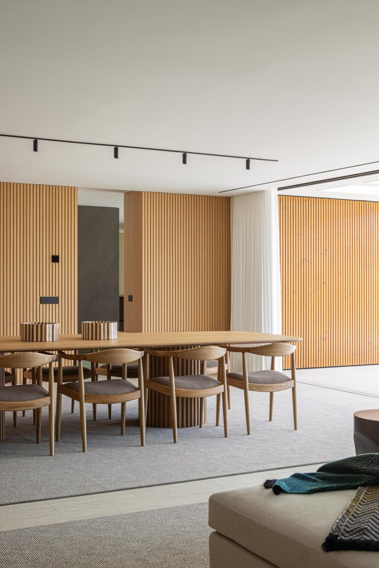 Zona de jantar com mesa em madeira mel, cadeiras em madeira escura e parede ripada em madeira mel — Casa FJ arquitectura MIL870 + GRAUON fotografia Ivo Tavares