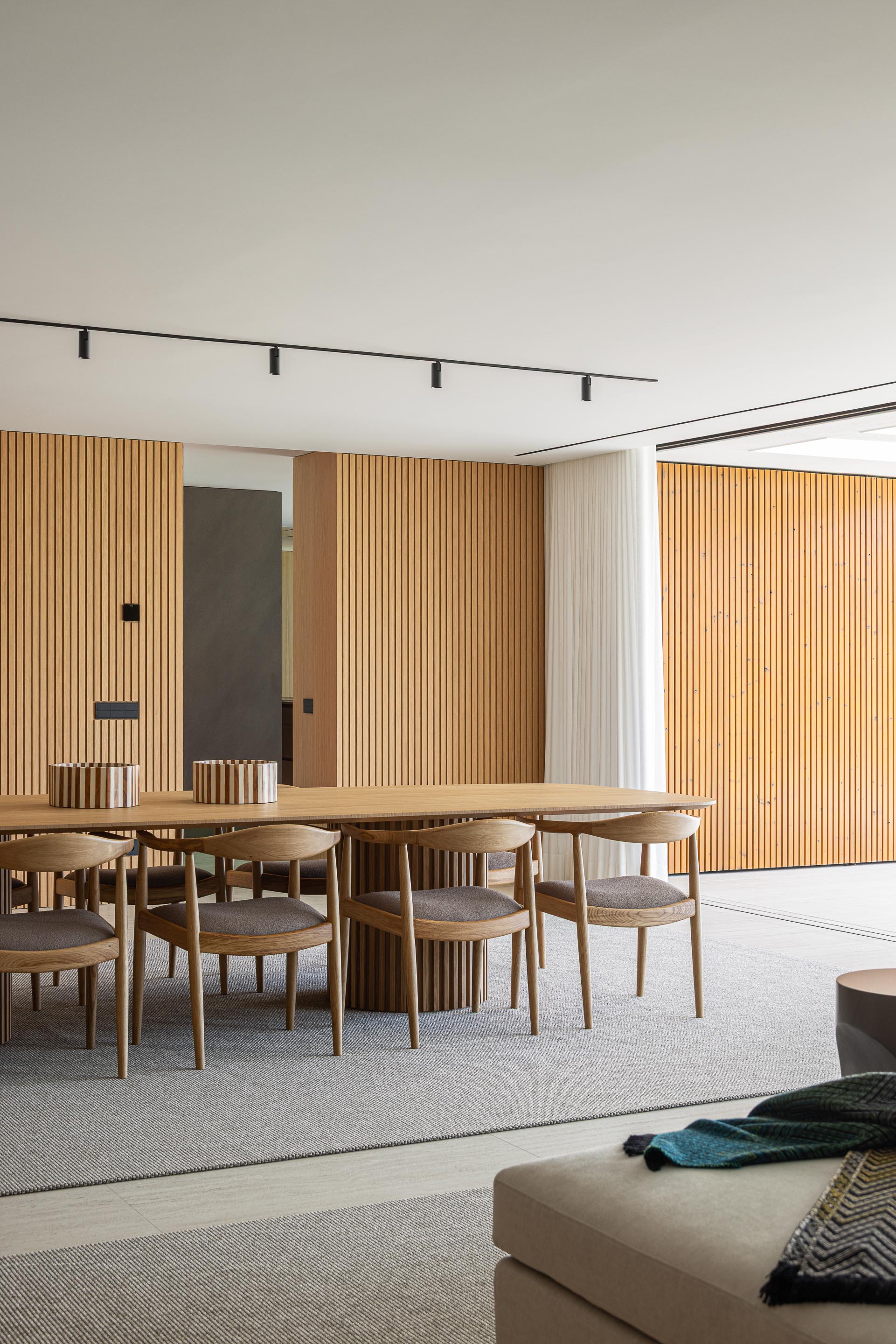 Zona de jantar com mesa em madeira mel, cadeiras em madeira escura e parede ripada em madeira mel — Casa FJ arquitectura MIL870 + GRAUON fotografia Ivo Tavares