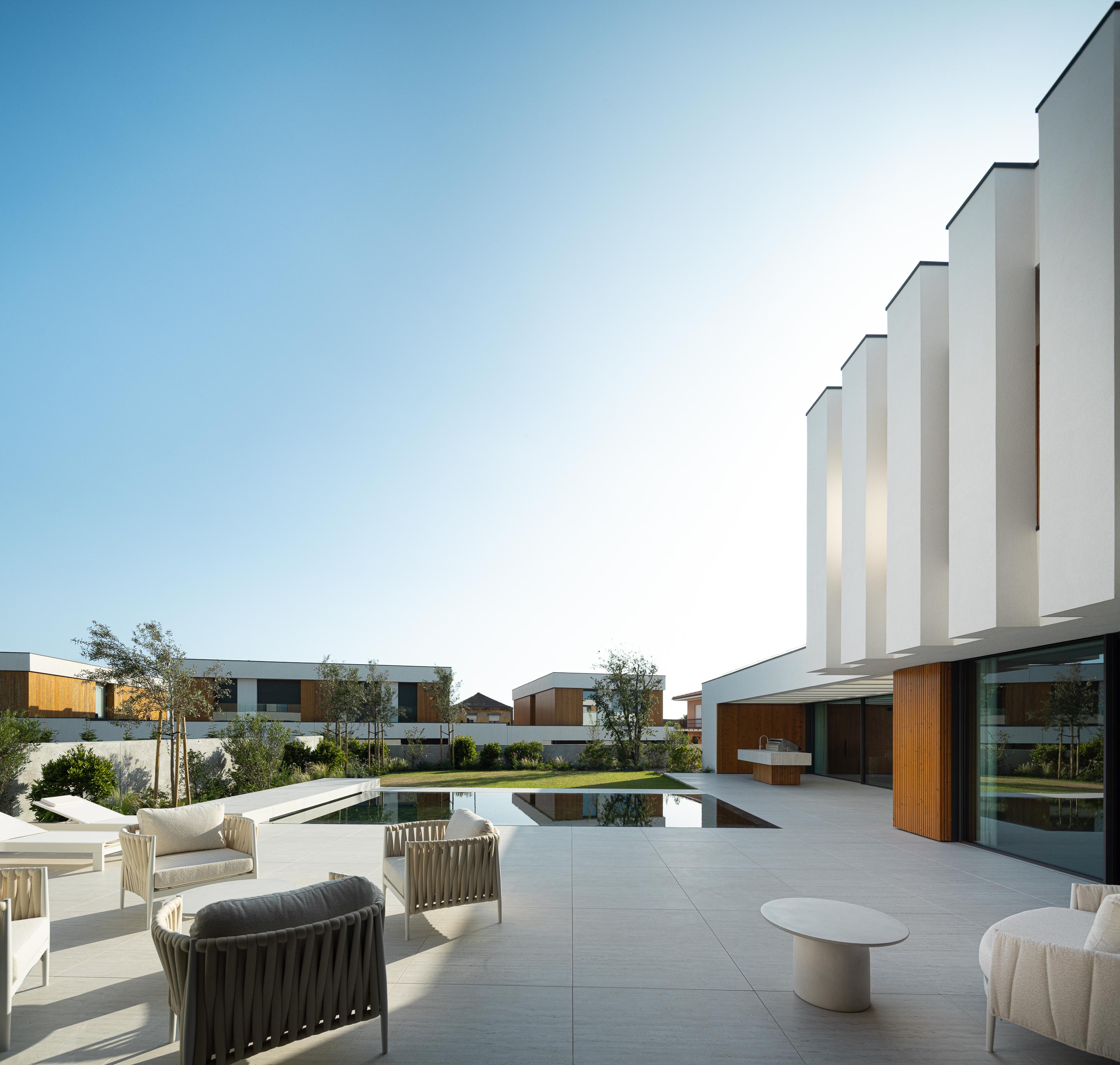 Zona da piscina com piscina retangular, pavimento em pedra clara e volumes brancos da moradia — Casa FJ arquitectura MIL870 + GRAUON fotografia Ivo Tavares