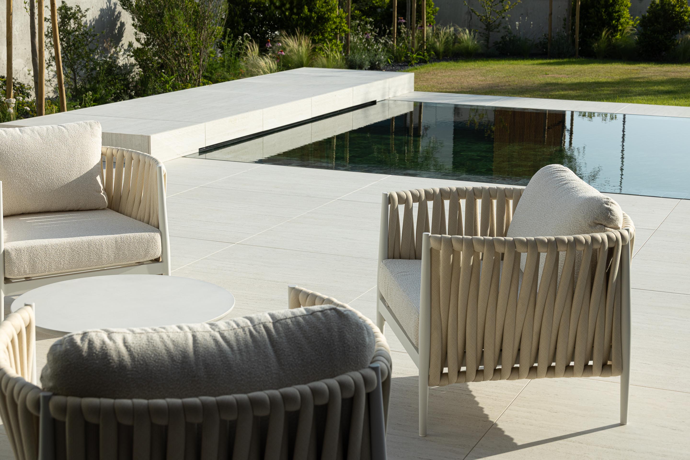 Zona da piscina com mobiliário de exterior em tons claros, pavimento em pedra clara e borda infinita — Casa FJ arquitectura MIL870 + GRAUON fotografia Ivo Tavares