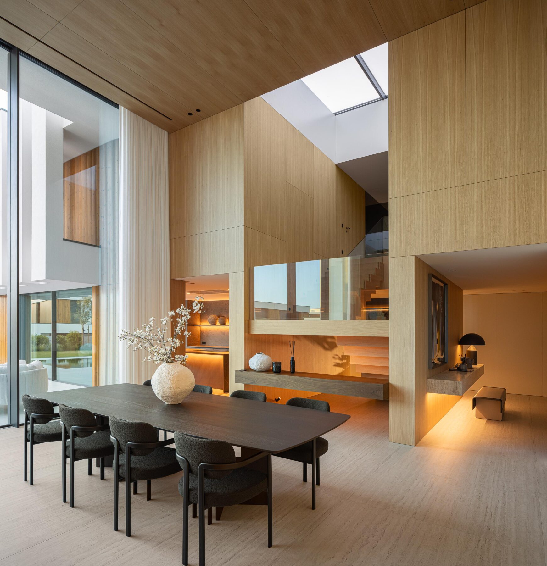 Sala de jantar com mesa escura, paredes em madeira mel e iluminação zenital no pé-direito duplo — Casa FJ arquitectura MIL870 + GRAUON fotografia Ivo Tavares