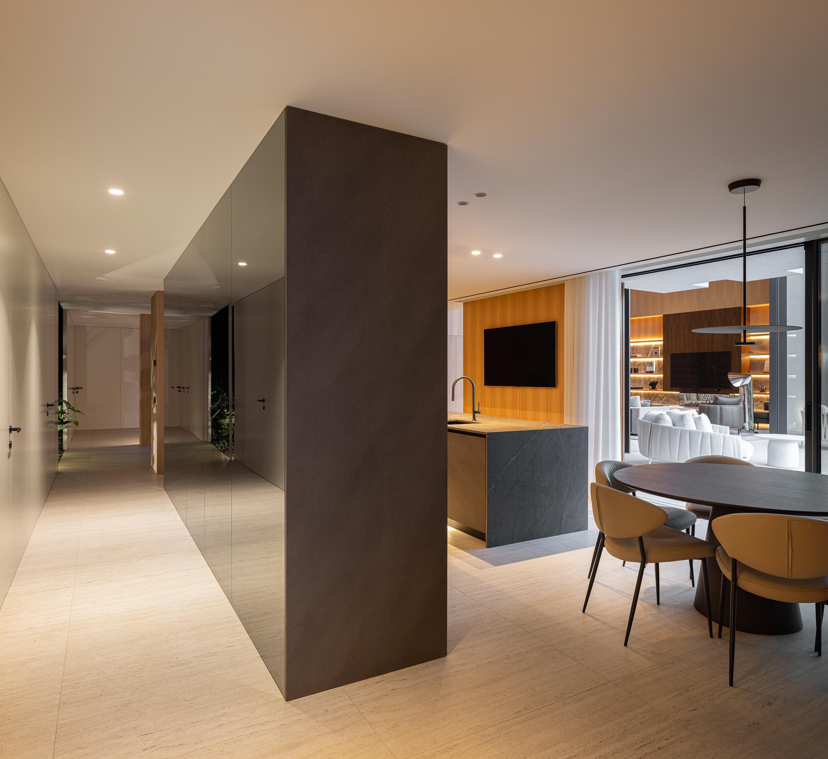 Cozinha com ilha em pedra escura, pavimento em pedra clara e corredor iluminado — Casa FJ arquitectura MIL870 + GRAUON fotografia Ivo Tavares