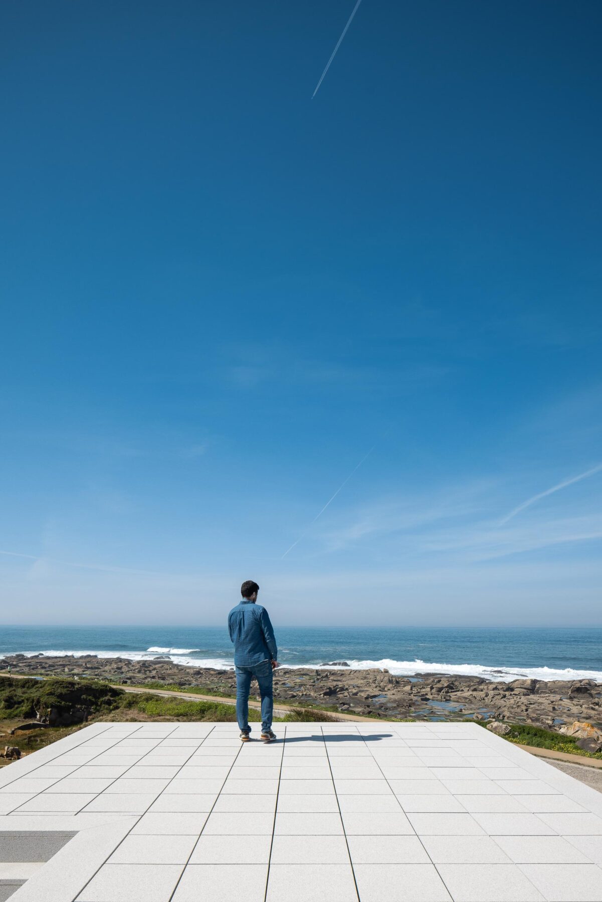 Terraço plano em lajetas claras, com pessoa a contemplar a vasta paisagem marítima — CASA ÂNCORA arquitectura Tiago Sousa Arquitecto fotografia Ivo Tavares