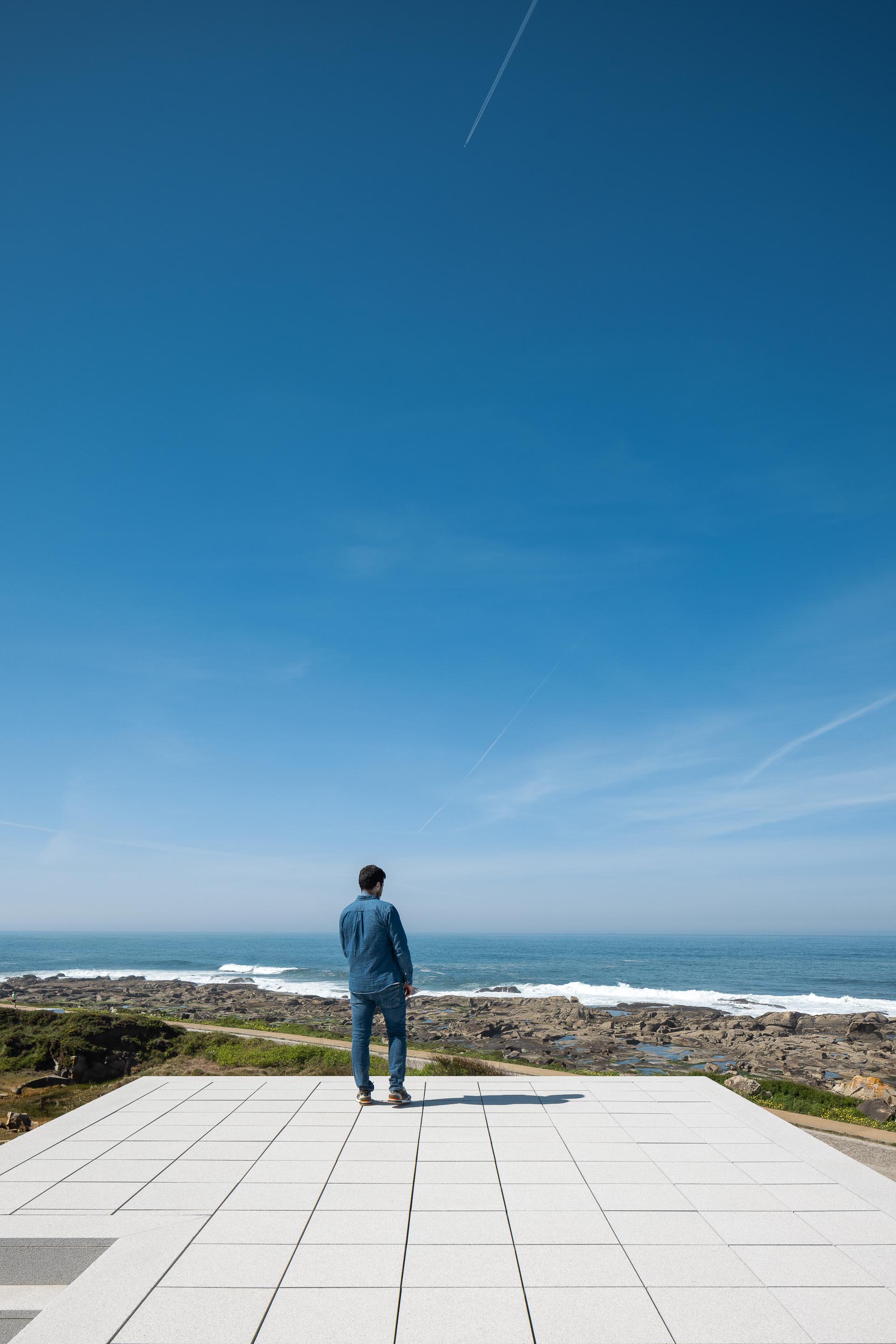 Terraço plano em lajetas claras, com pessoa a contemplar a vasta paisagem marítima — CASA ÂNCORA arquitectura Tiago Sousa Arquitecto fotografia Ivo Tavares