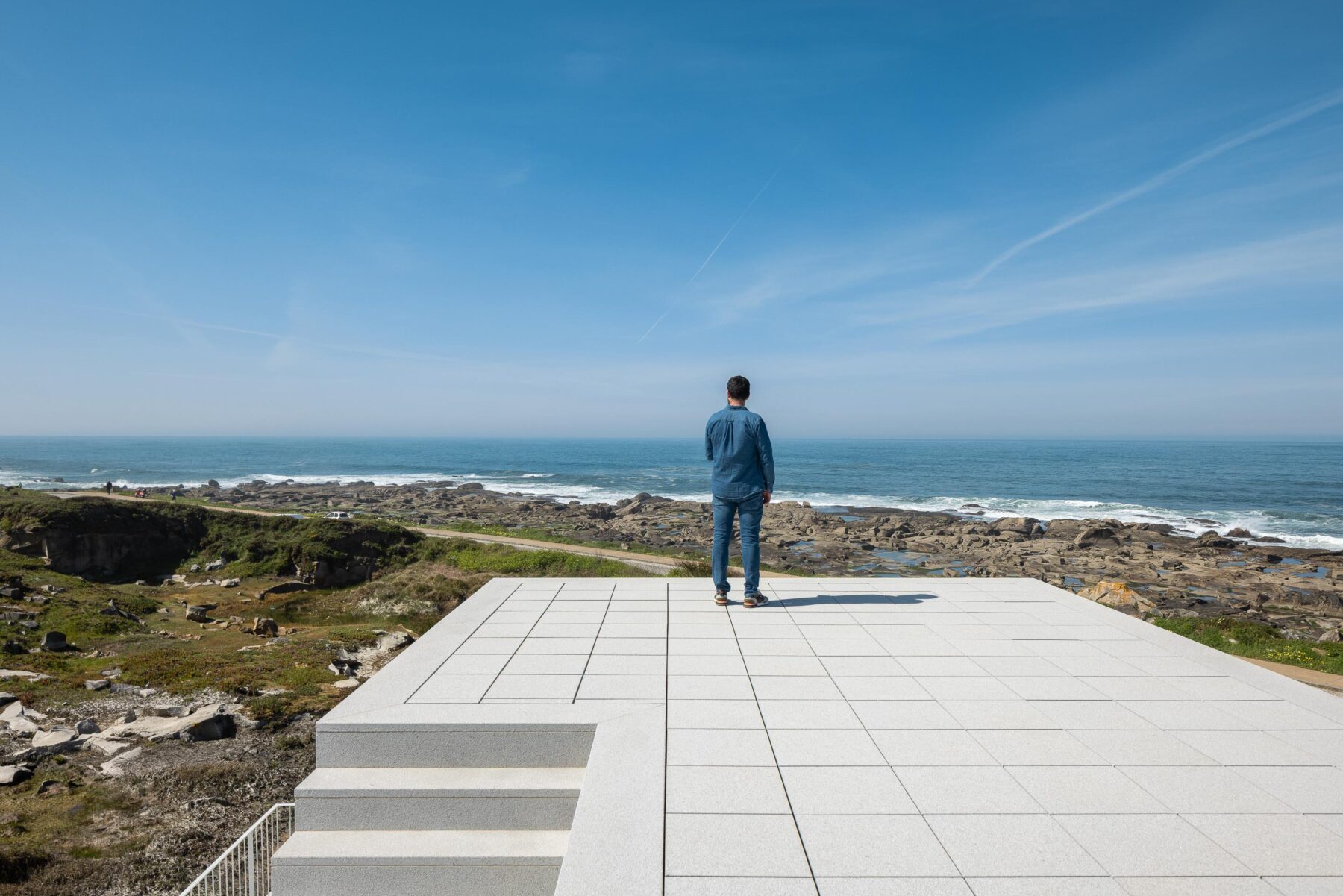 Terraço em lajetas claras com degraus, oferecendo vista panorâmica para o mar e costa rochosa — CASA ÂNCORA arquitectura Tiago Sousa Arquitecto fotografia Ivo Tavares