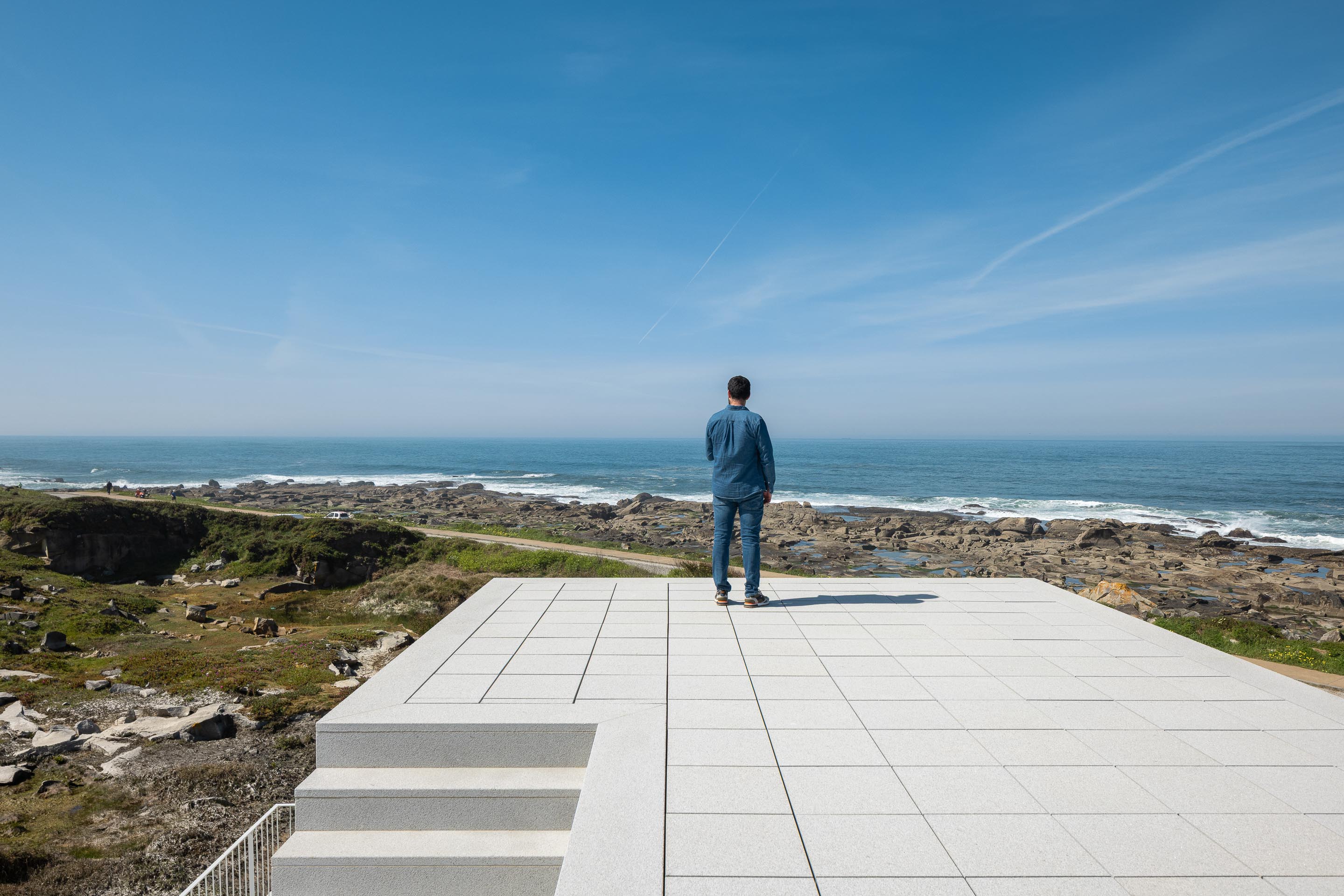 Terraço em lajetas claras com degraus, oferecendo vista panorâmica para o mar e costa rochosa — CASA ÂNCORA arquitectura Tiago Sousa Arquitecto fotografia Ivo Tavares
