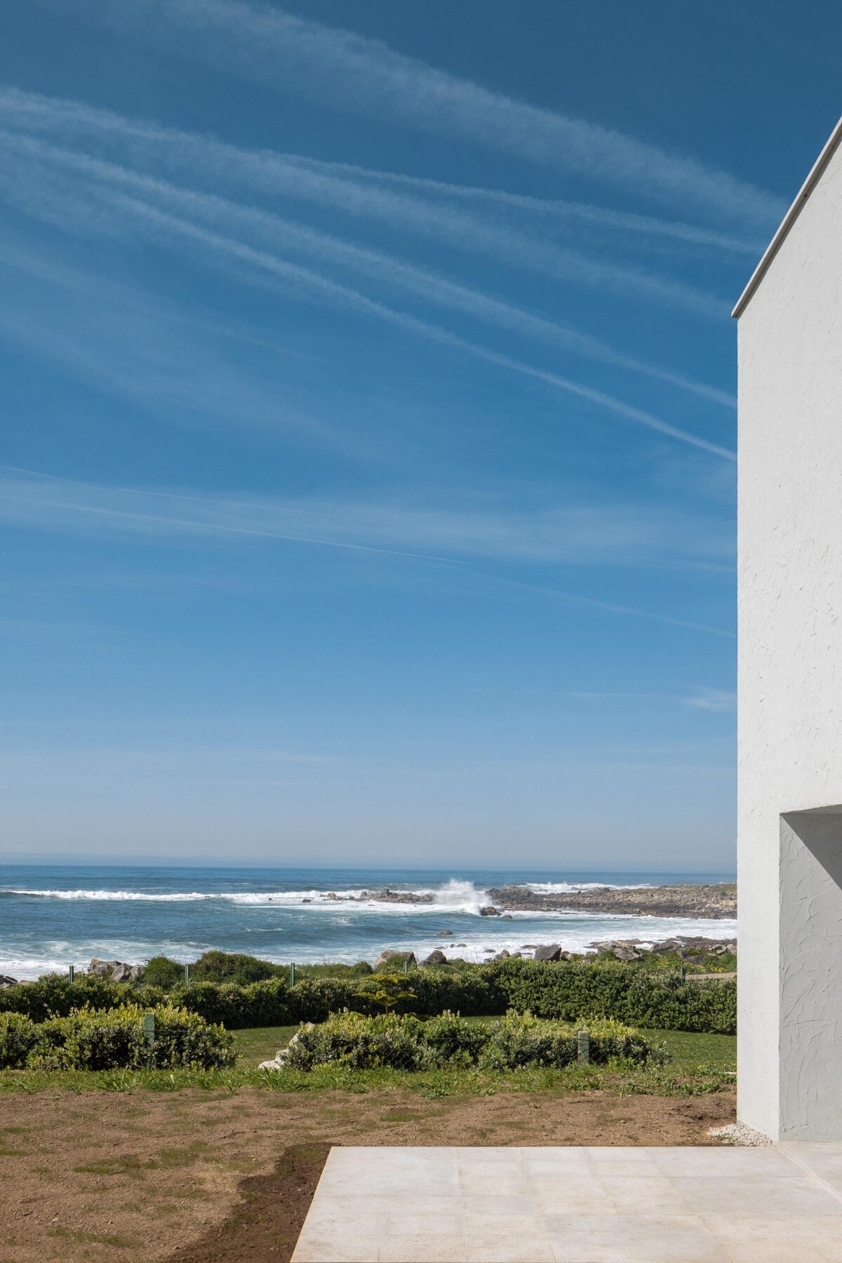 Terraço exterior com pavimento claro, em contacto direto com a vegetação e o mar — CASA ÂNCORA arquitectura Tiago Sousa Arquitecto fotografia Ivo Tavares