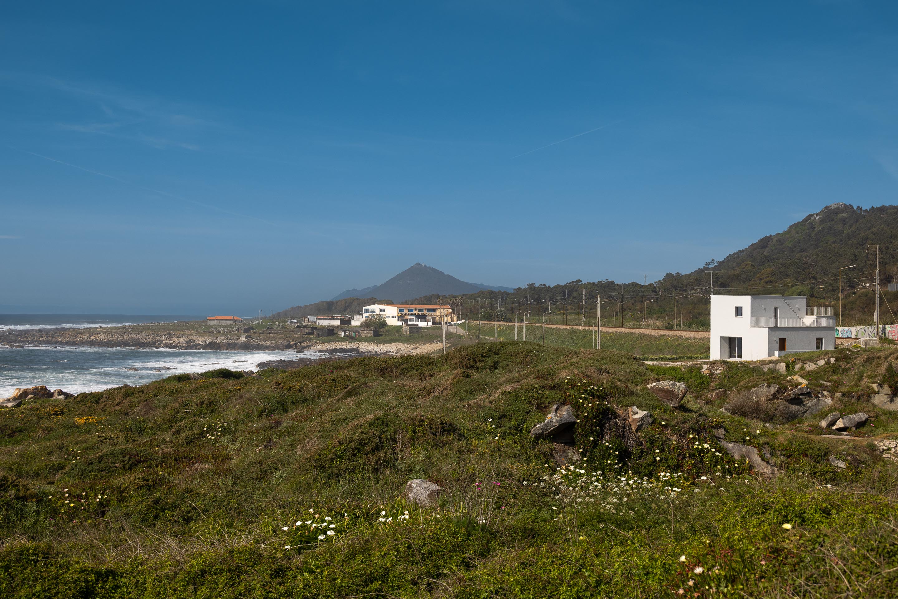Moradia branca de volumes compactos, integrada na paisagem costeira e montanhosa — CASA ÂNCORA arquitectura Tiago Sousa Arquitecto fotografia Ivo Tavares
