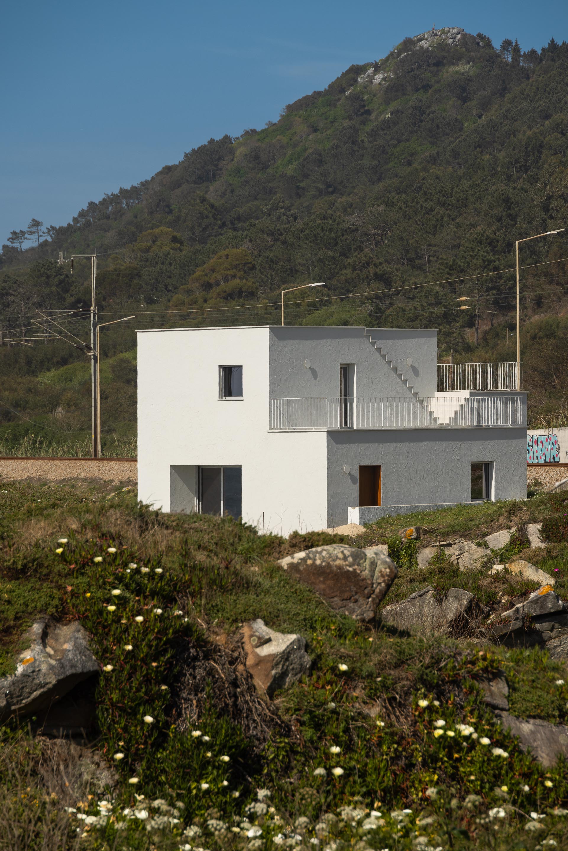 Moradia branca com volumes escalonados e escadarias exteriores, inserida na encosta rochosa — CASA ÂNCORA arquitectura Tiago Sousa Arquitecto fotografia Ivo Tavares