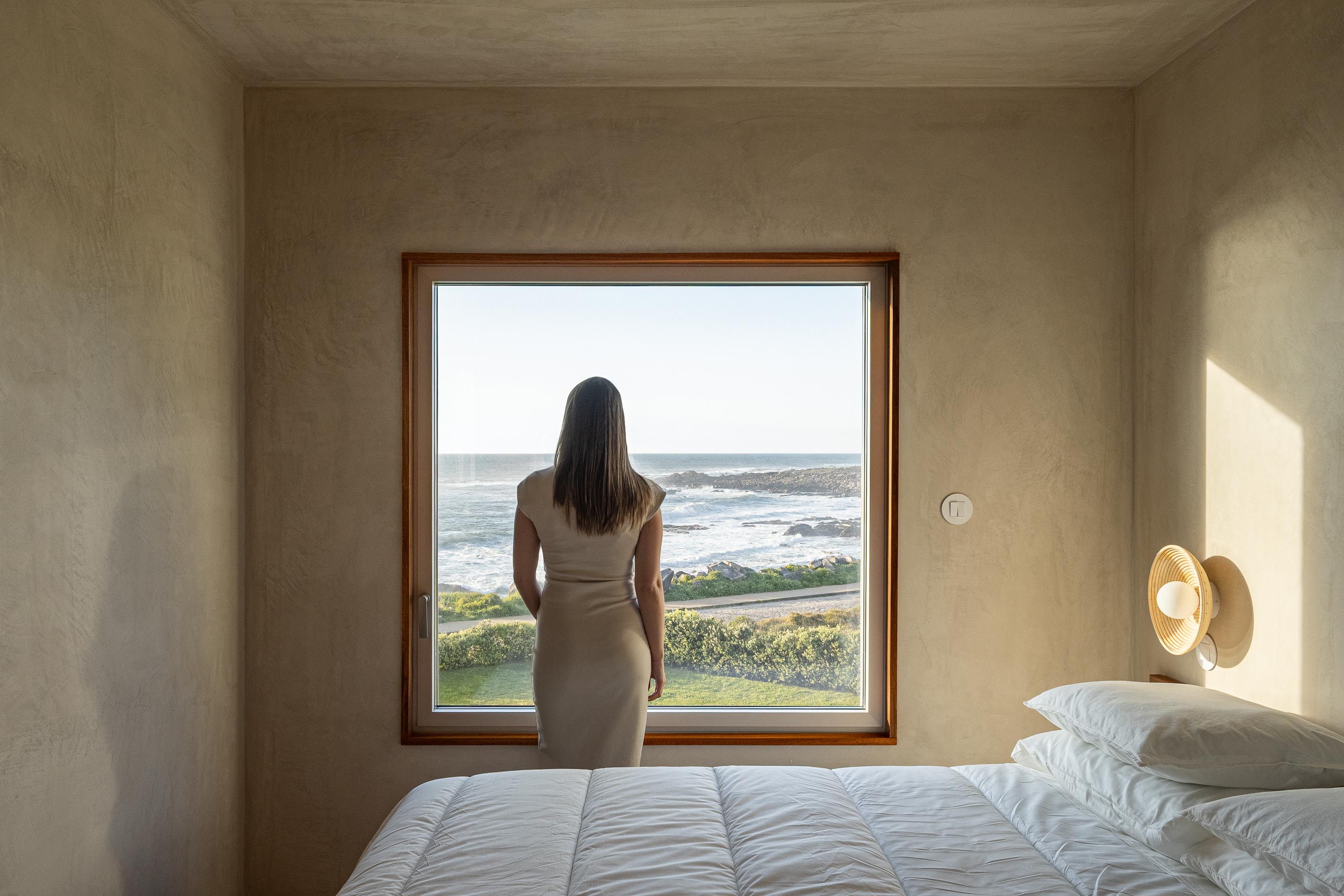 Quarto com pavimento cerâmico de barro e paredes em gesso projetado, com grande vão para o mar — CASA ÂNCORA arquitectura Tiago Sousa Arquitecto fotografia Ivo Tavares